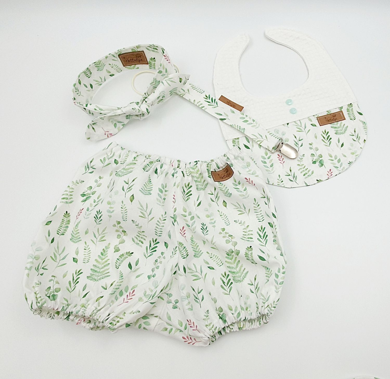 Baby girl floral bloomers set with matching headband and bib, white fabric with green leaf print.