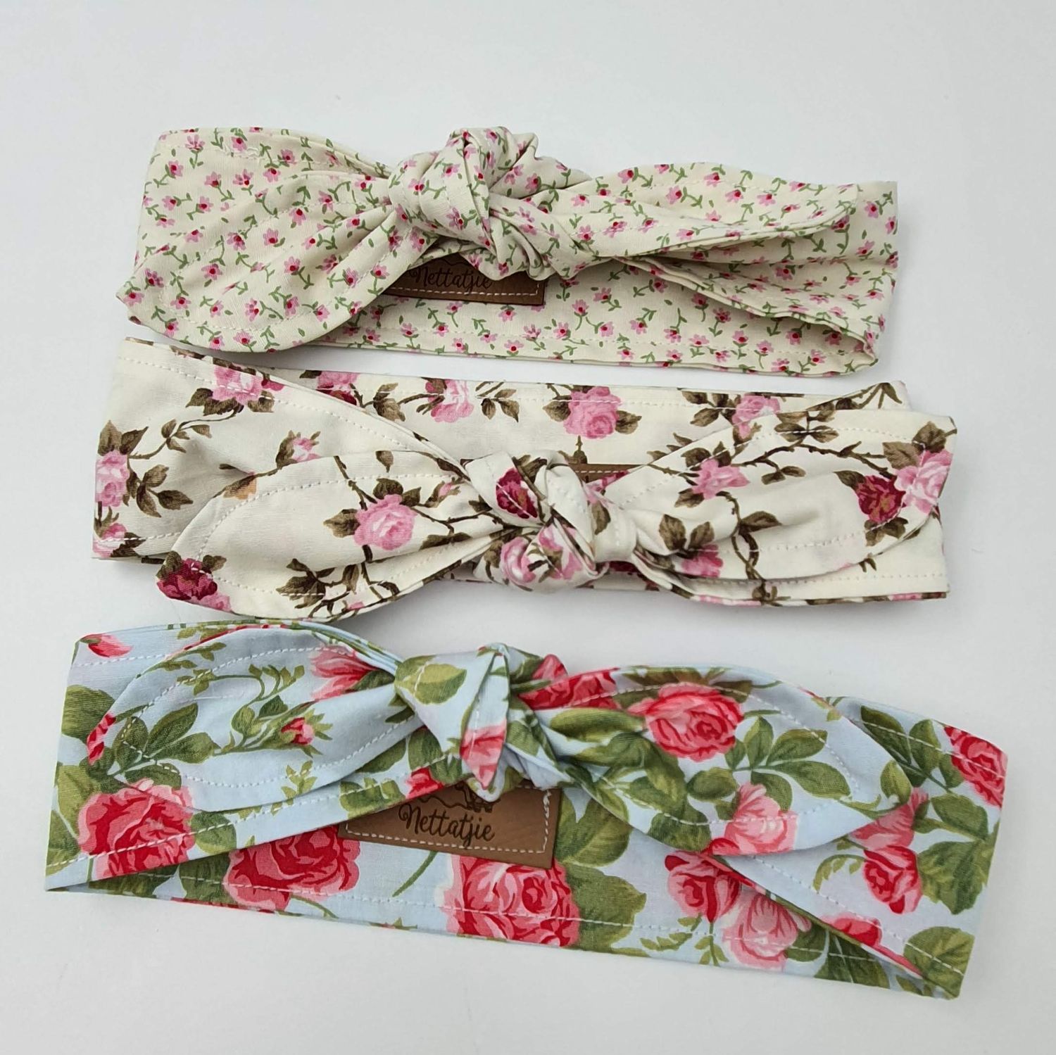 Floral print fabric headbands with pink roses and cream background displayed in various angles.
