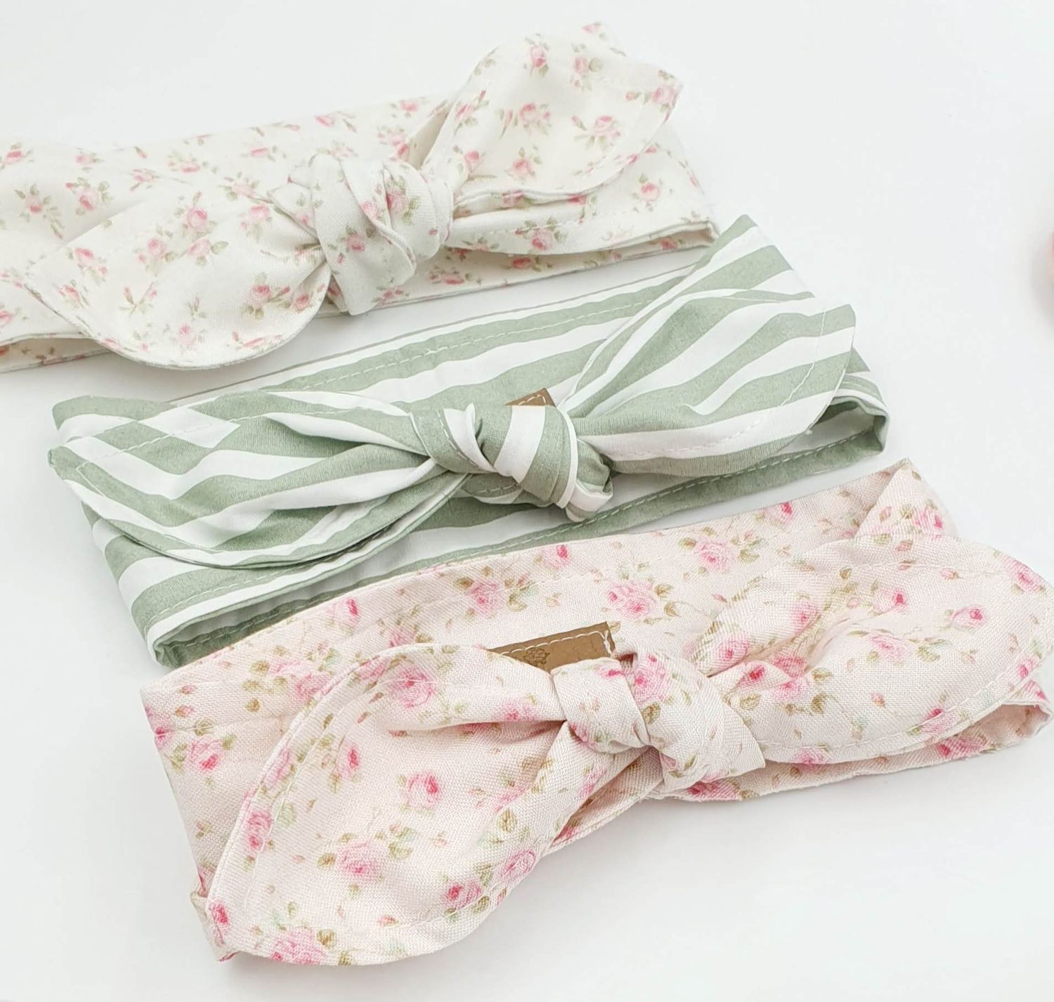 Delicate pink and sage green floral pattern headbands with bow details laid flat.
