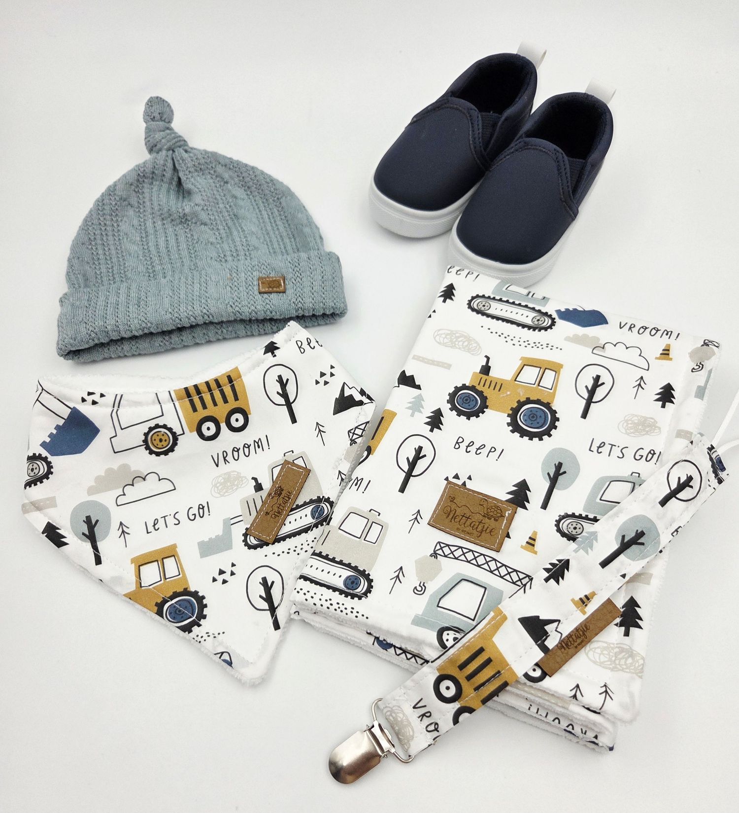 Baby boy set with construction vehicle print fabric, blue knit beanie, and navy shoes.