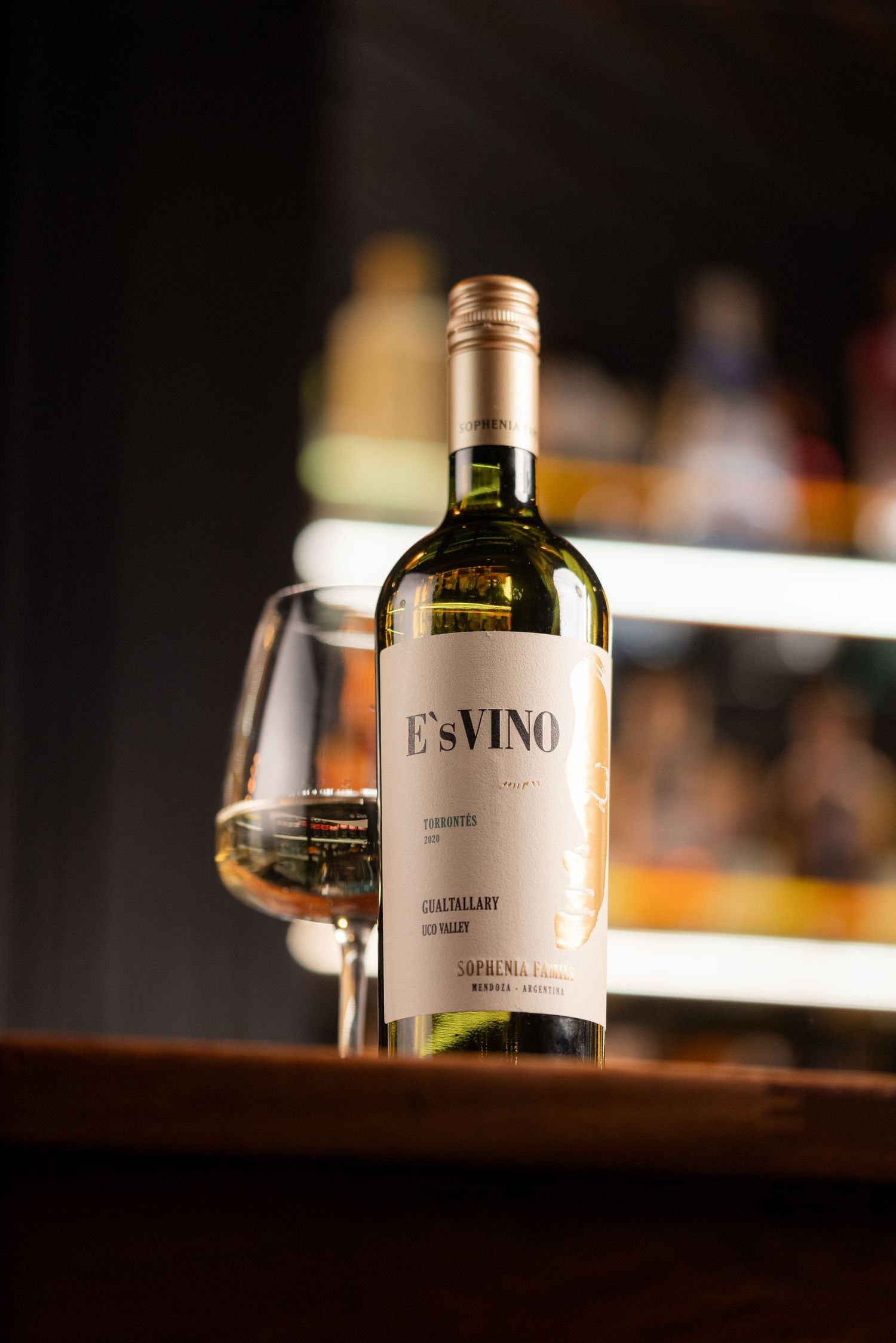 Bottle of white wine with glass on a bar counter with warm bokeh lighting, wine and drinks product photography Southampton