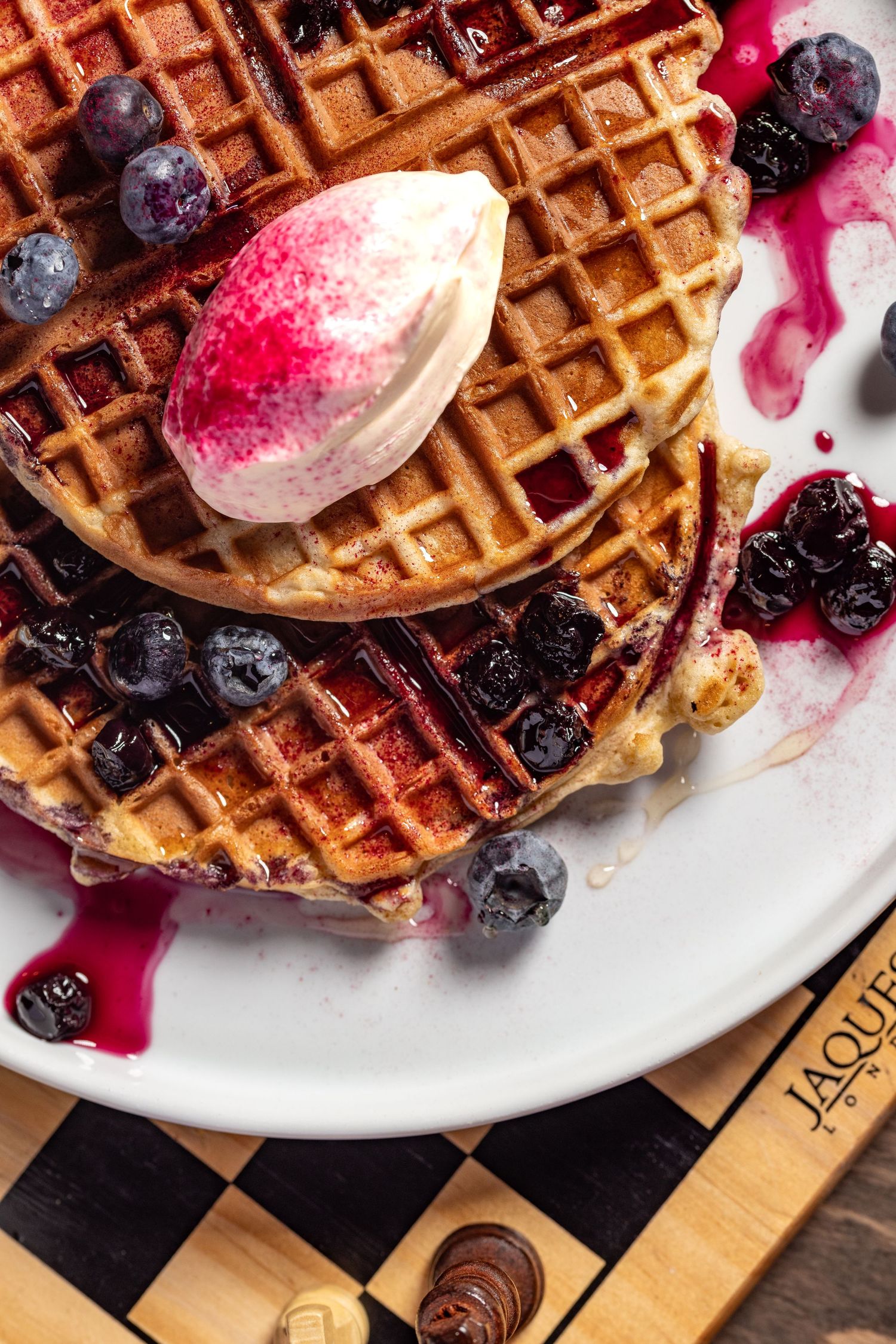 Stacked Belgian waffles with blueberries, berry compote and pink macaron, brunch menu food photography Southampton