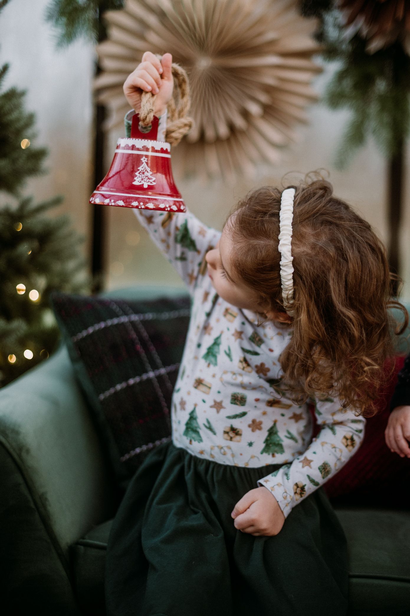 Child in holiday pajamas plays with red and white Christmas decorations in a cozy living room setting.