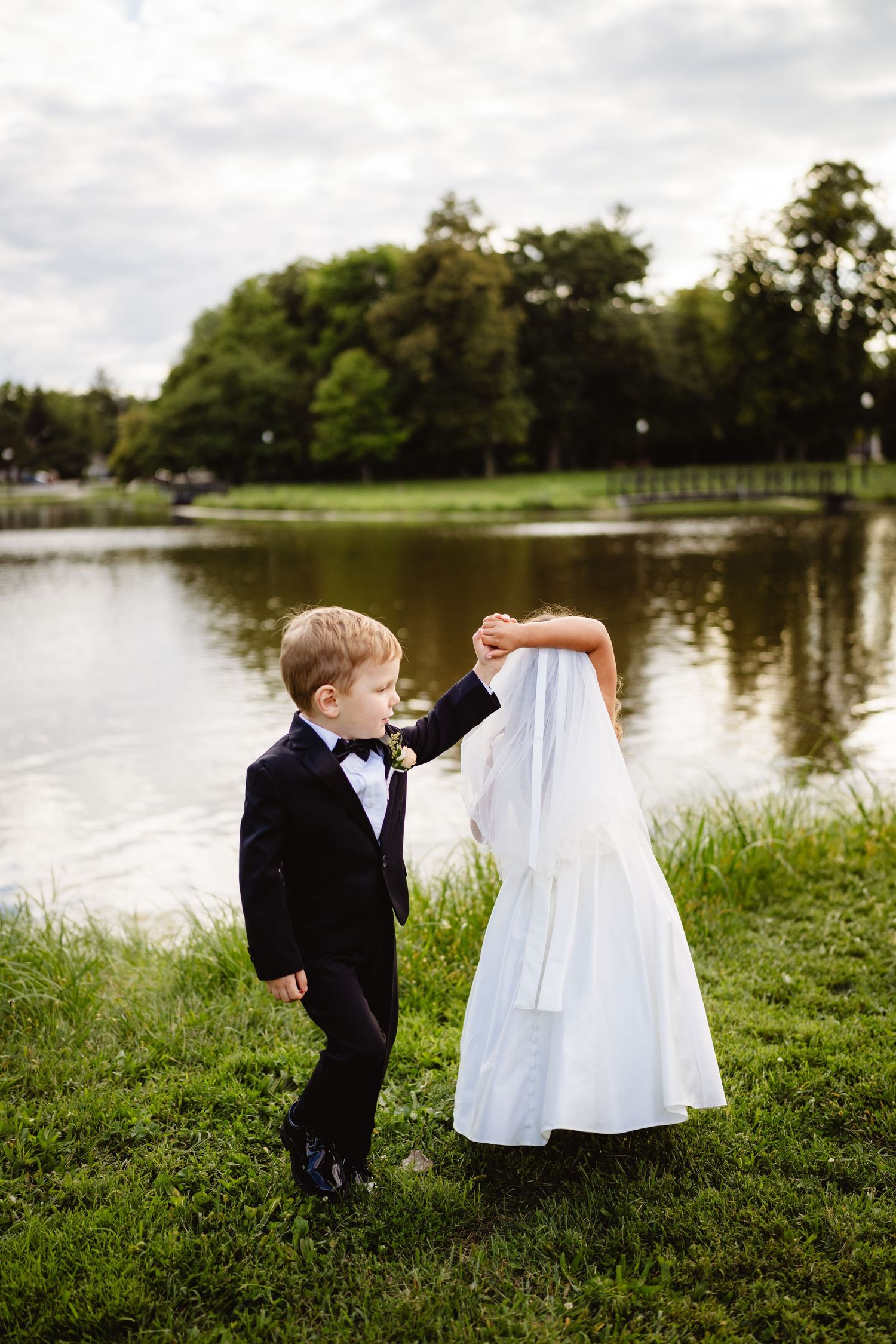 A sequence of four photos shows a playful moment by a lake as a child peeks behind a flowing white dress.