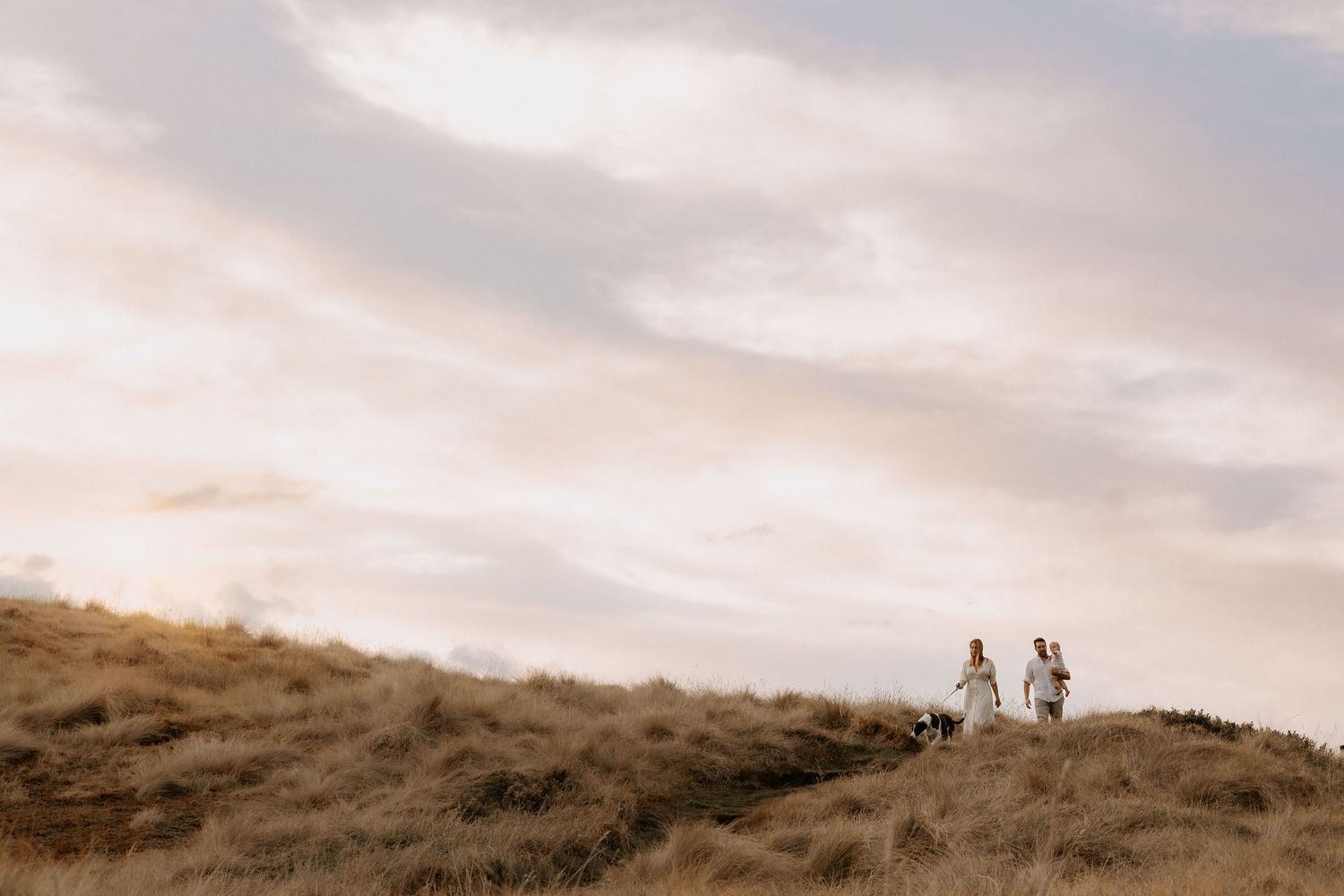 Cyclists ride along a scenic ridgeline trail against a golden sunset sky.