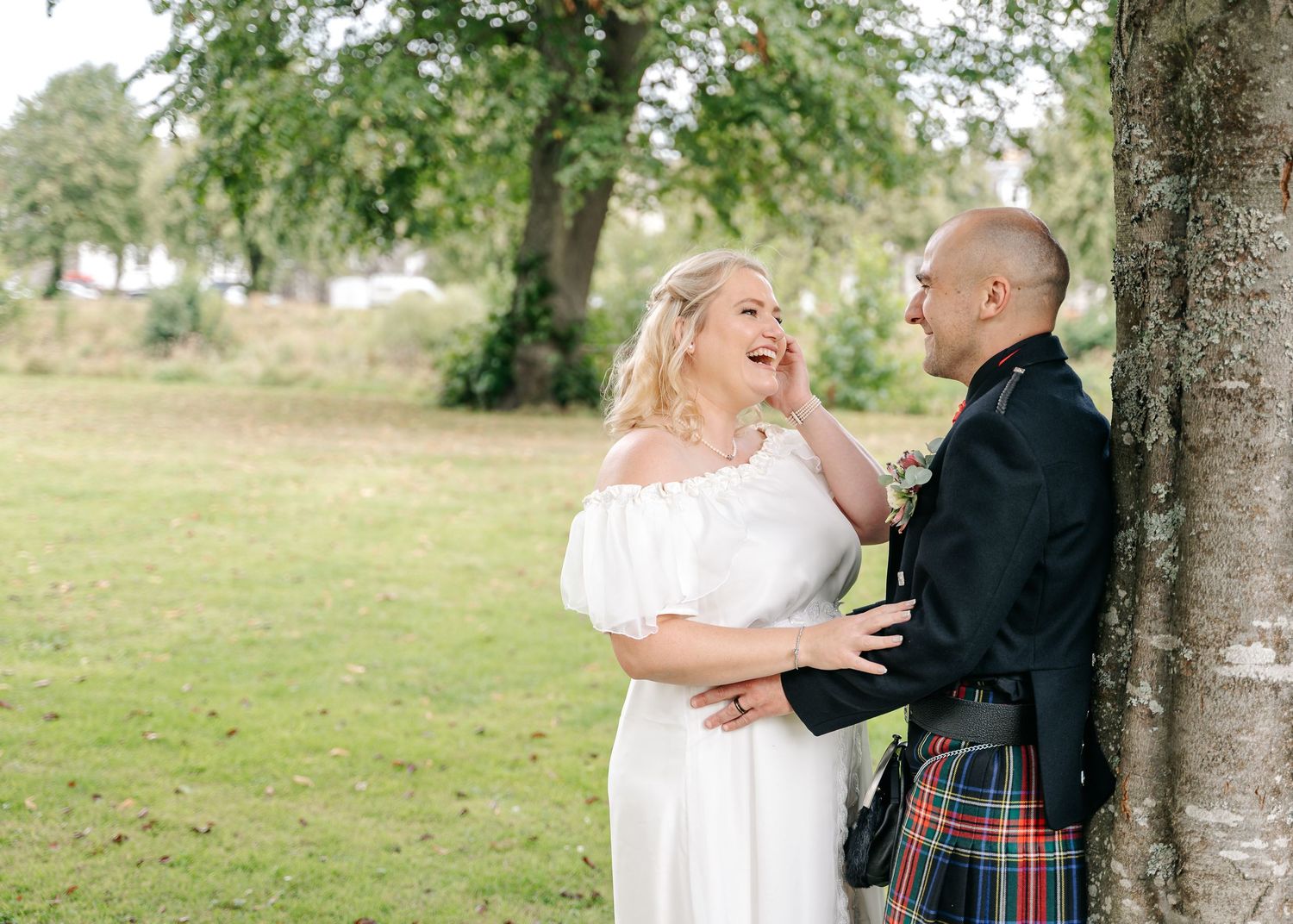 Romantic couple sharing tender moments in an outdoor garden setting near a river in Peebles.