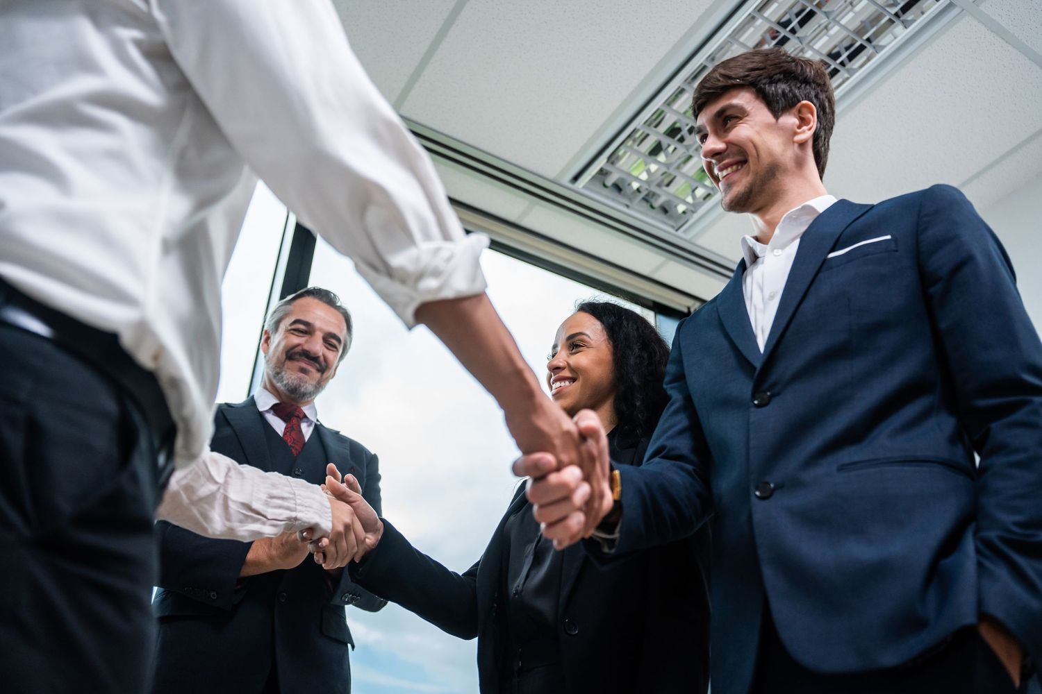 Business professionals shake hands and smile during a series of professional meetings in an office setting.