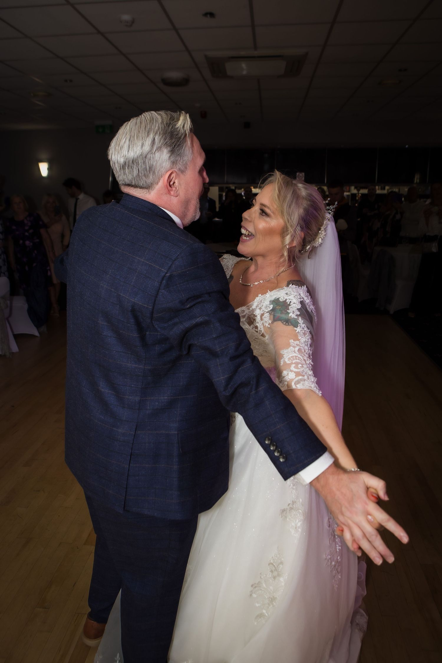 A couple shares romantic dance moments at their wedding reception in dimly lit venue with artistic framing.