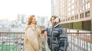 Couple wearing winter coats walking together through an urban area on a cloudy day.