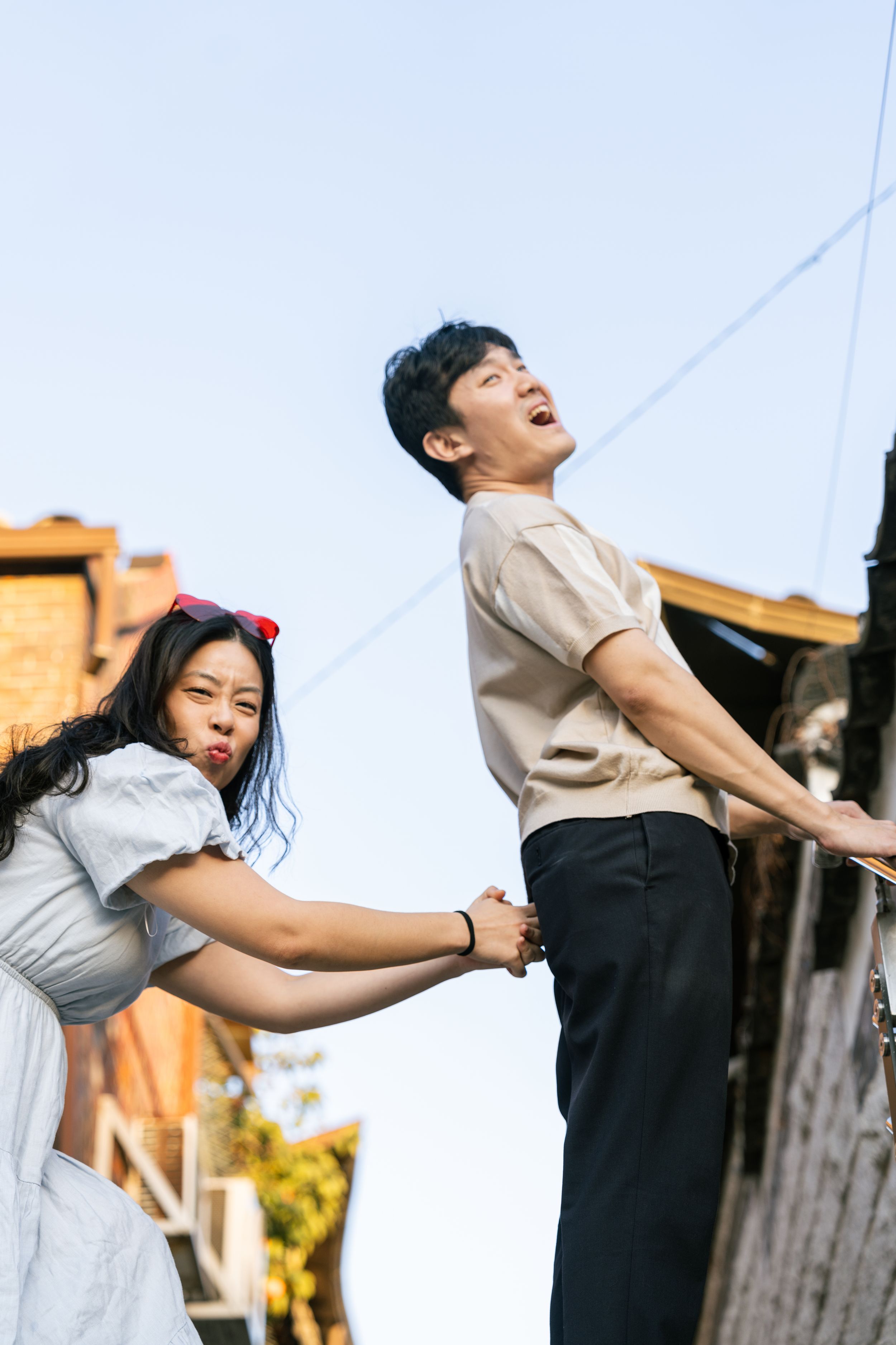 Playful couple in vintage style clothing posing against an urban backdrop.
