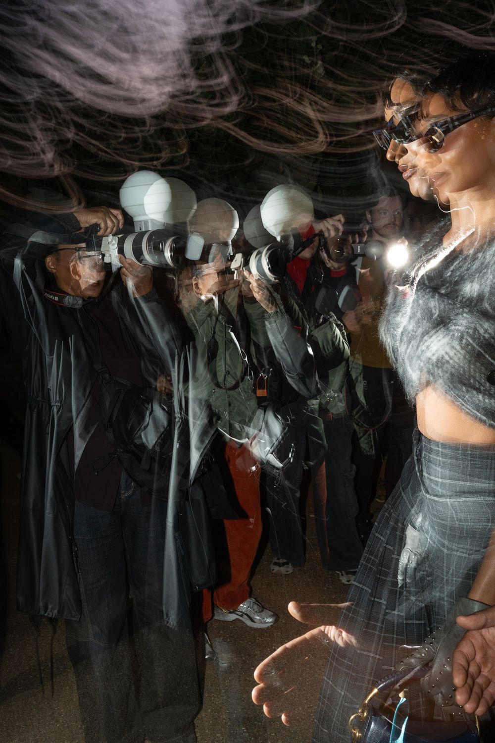 A celebrity wearing Burberry clothes walking through a crowd of photographers at London Fashion Week, UK
