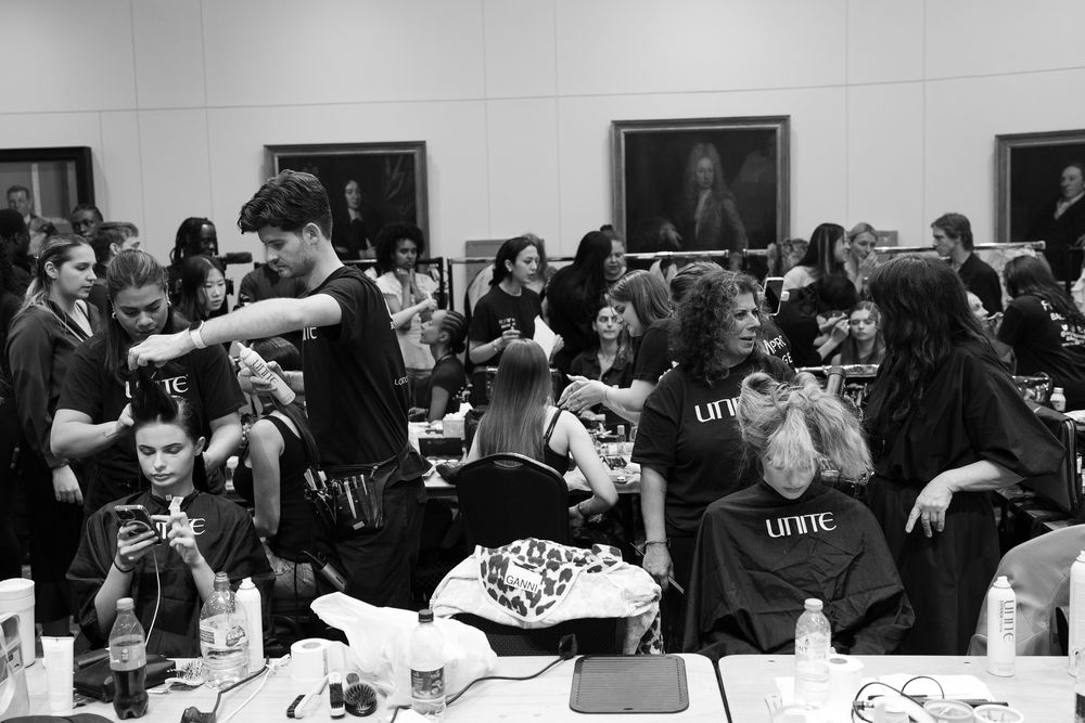 Black and white backstage photo of hairstylists and make-up artists preparing models for a fashion show in London