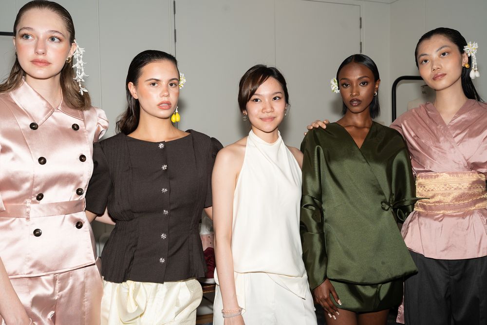 A lineup of models wearing neutral colors and minimalist designs stands together against a white background at Jimmy Choo Academy, London