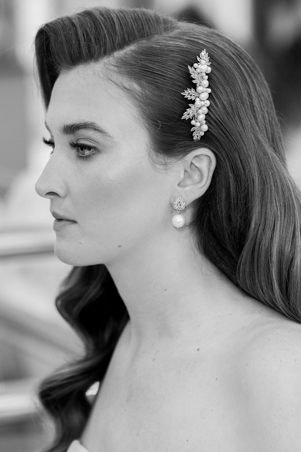 Black and white profile shot showing elegant bridal styling with a crystal hair accessory and pearl drop earring. Cambridge