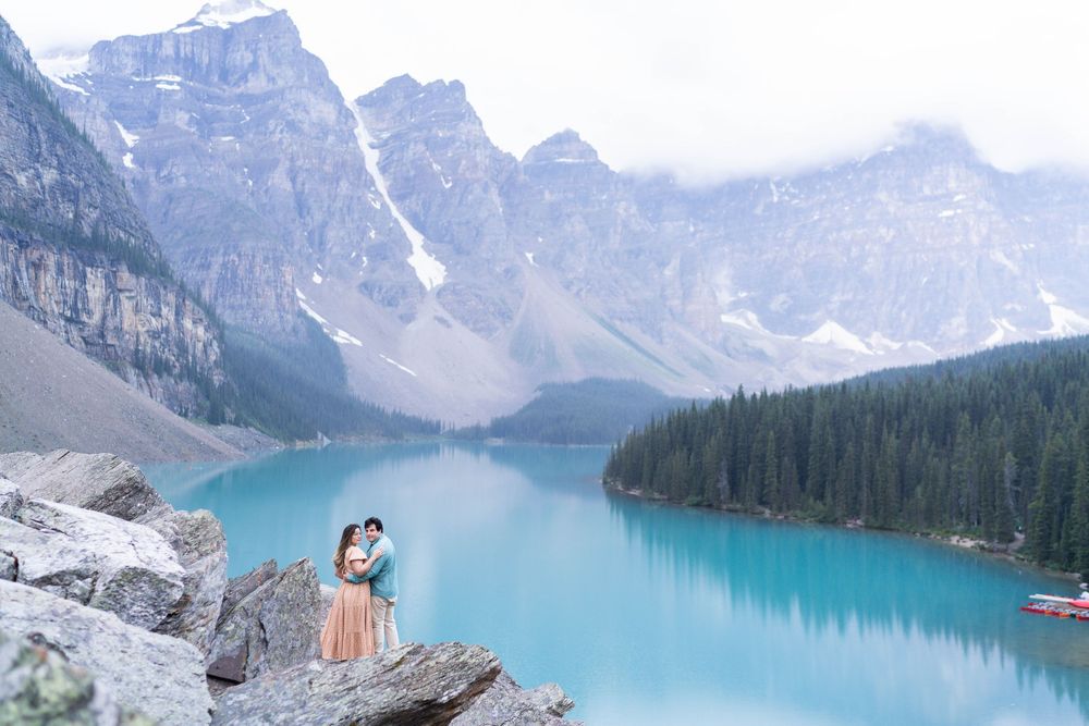 Two people in scenic mountain landscape overlooking vibrant blue alpine lake.