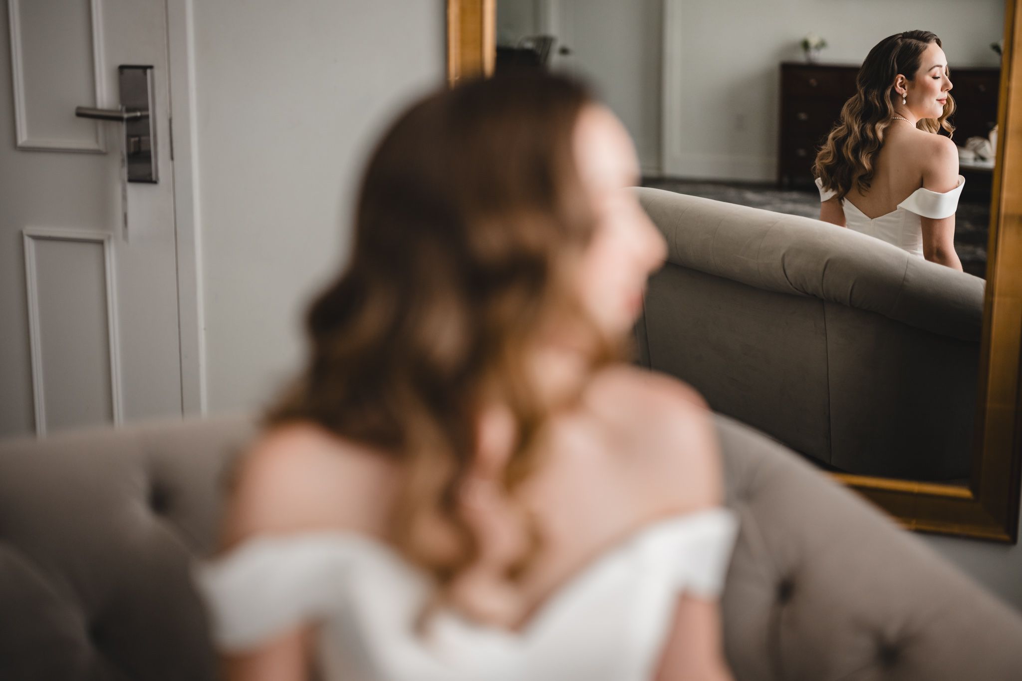 A classic bridal portrait showing the silhouette of a white wedding dress against a bright window.