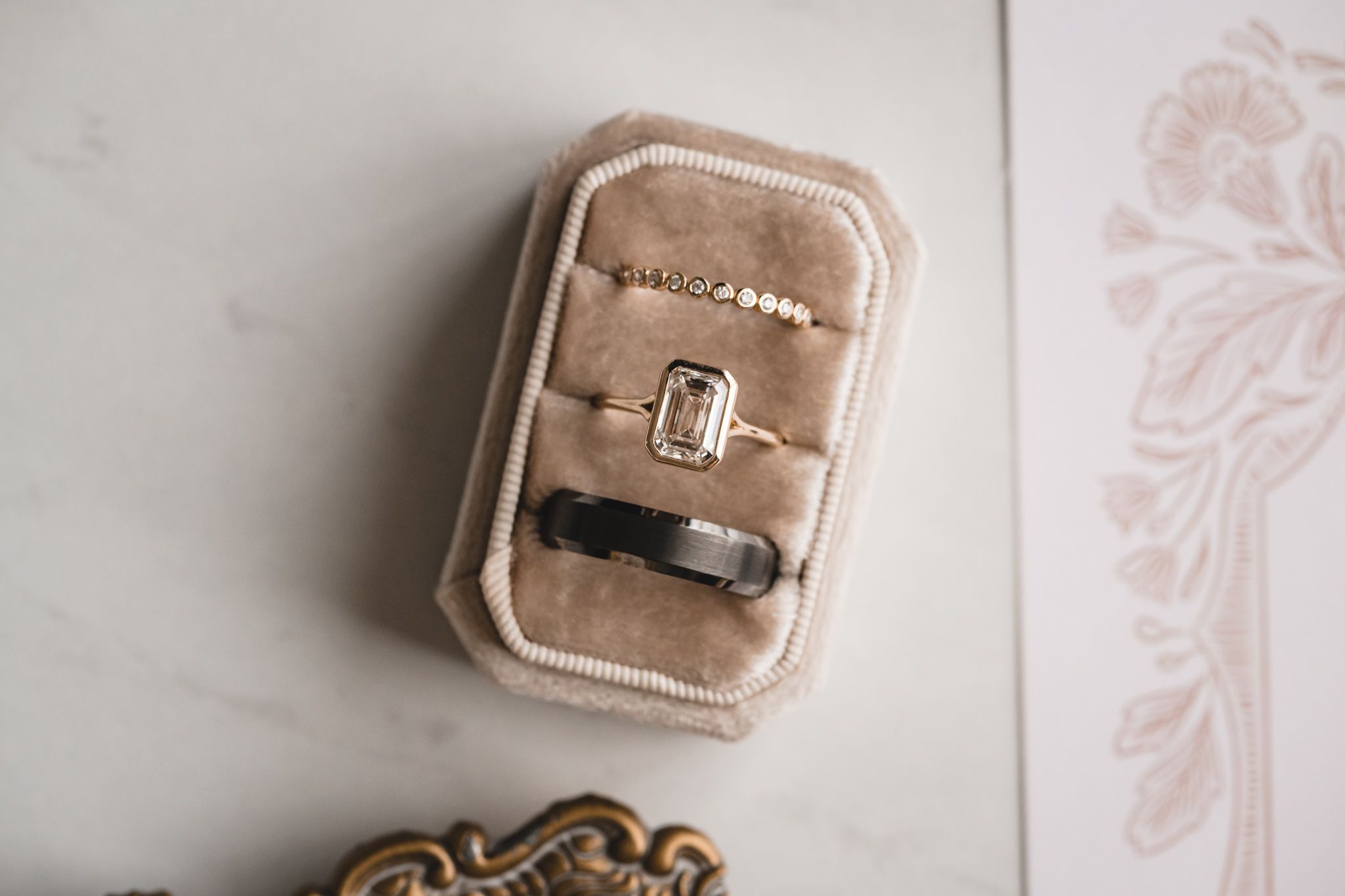 Close-up of wedding rings nestled in a blush velvet ring box with romantic styling.