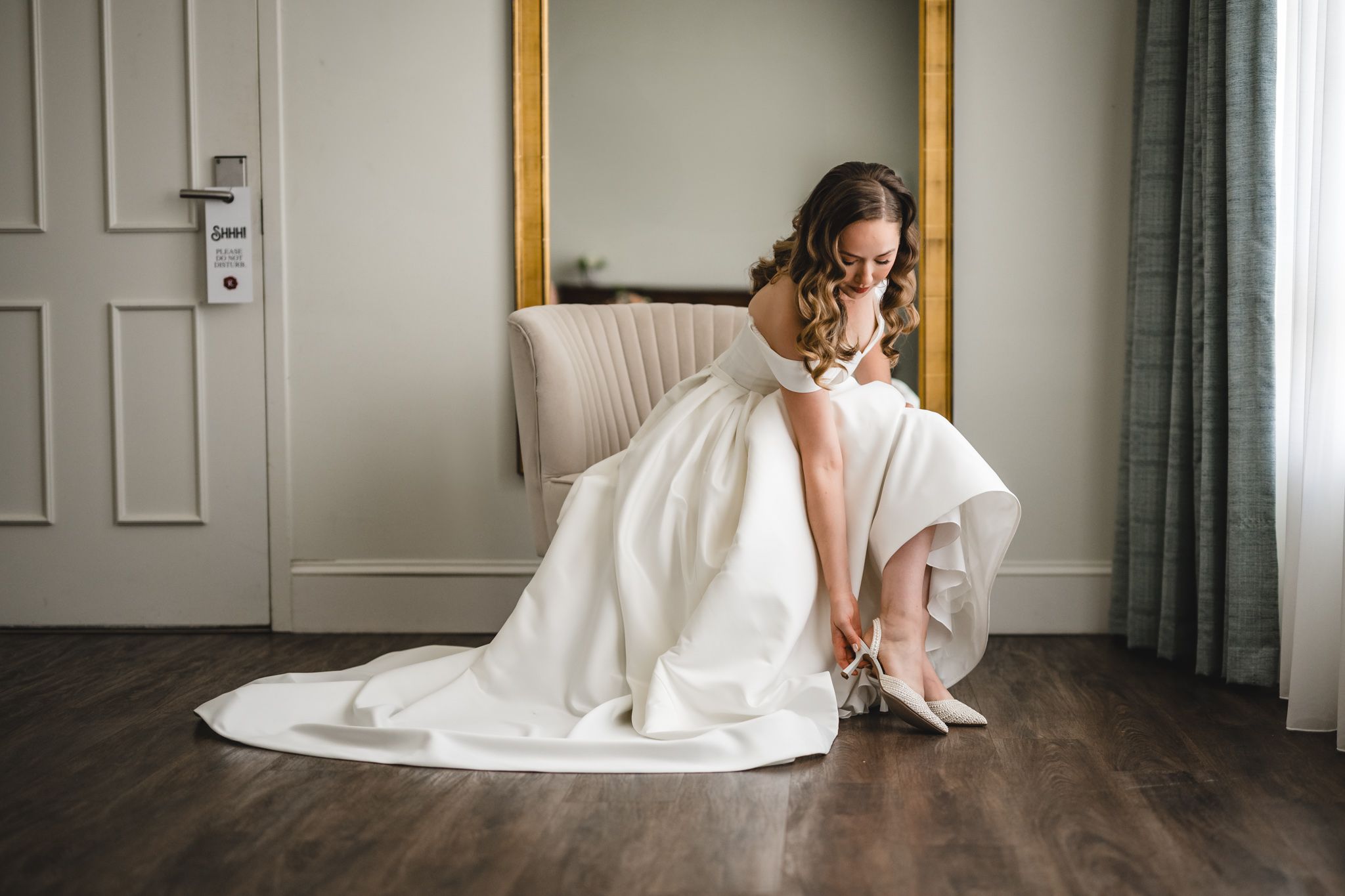 Artistic wedding day preparation scene with dress and decor in elegant room setting.