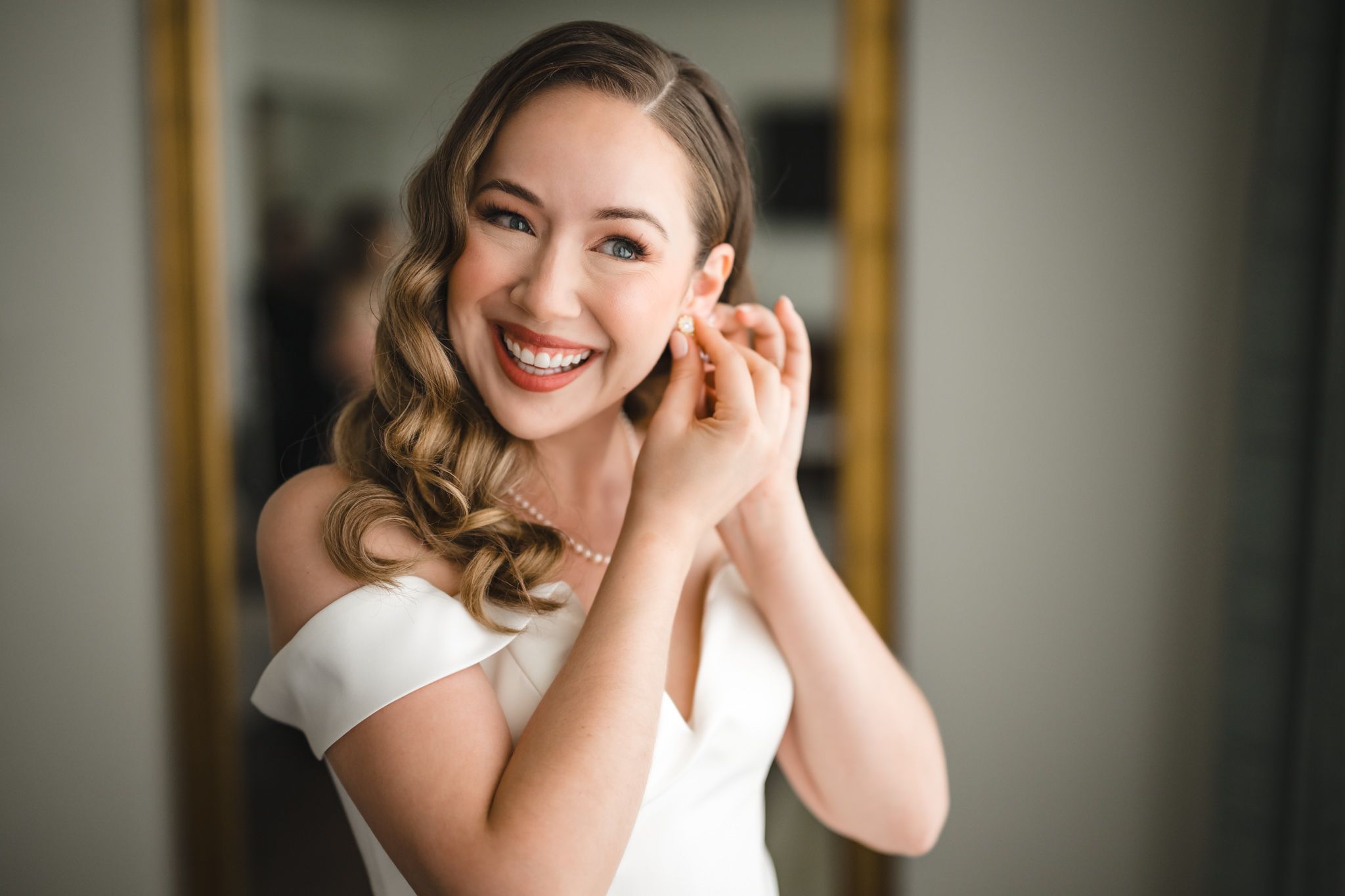 Joyful wedding preparation scene with white dress and natural window lighting.