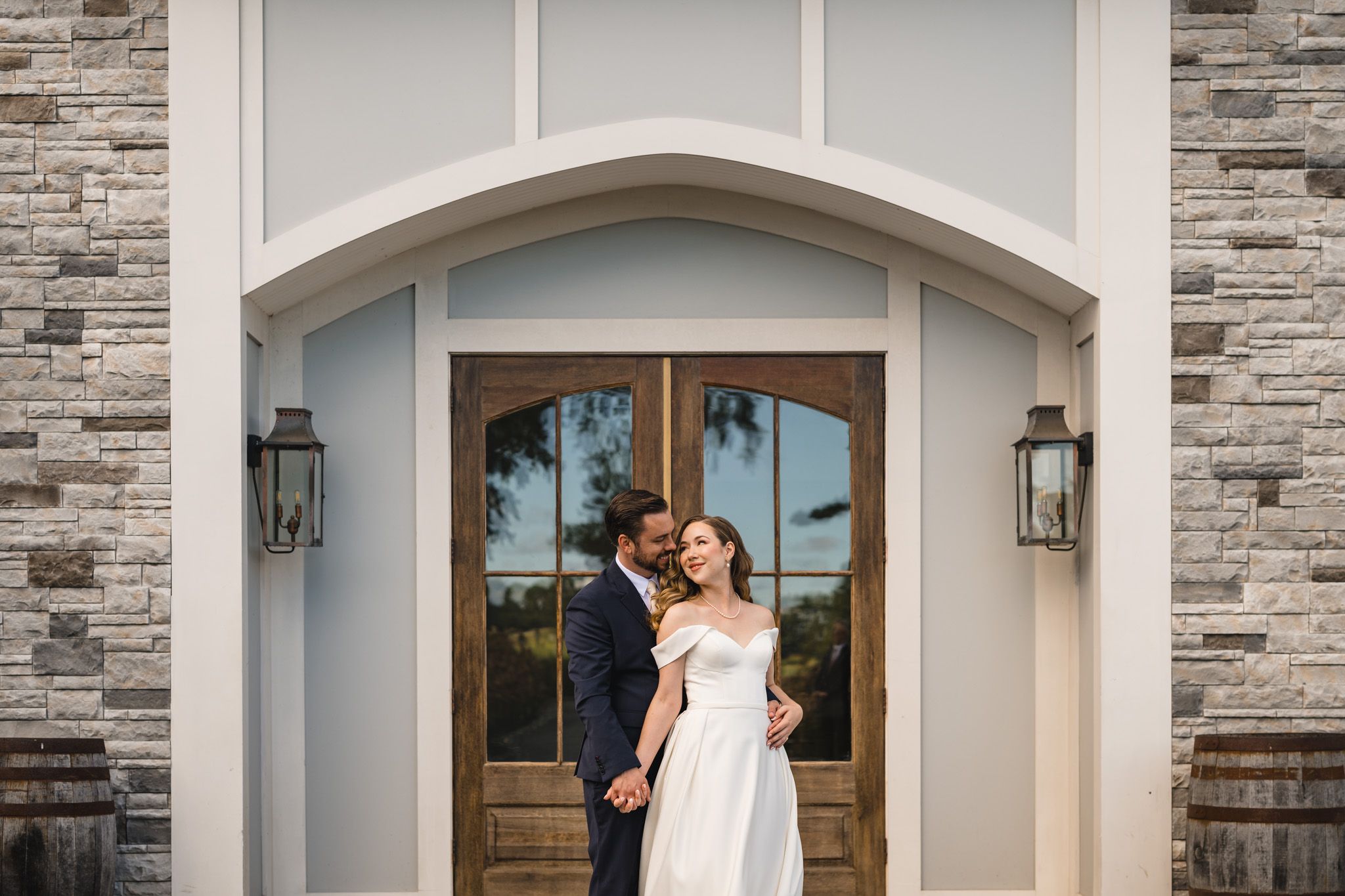 A couple shares a romantic moment in front of an elegant stone entrance with lanterns.