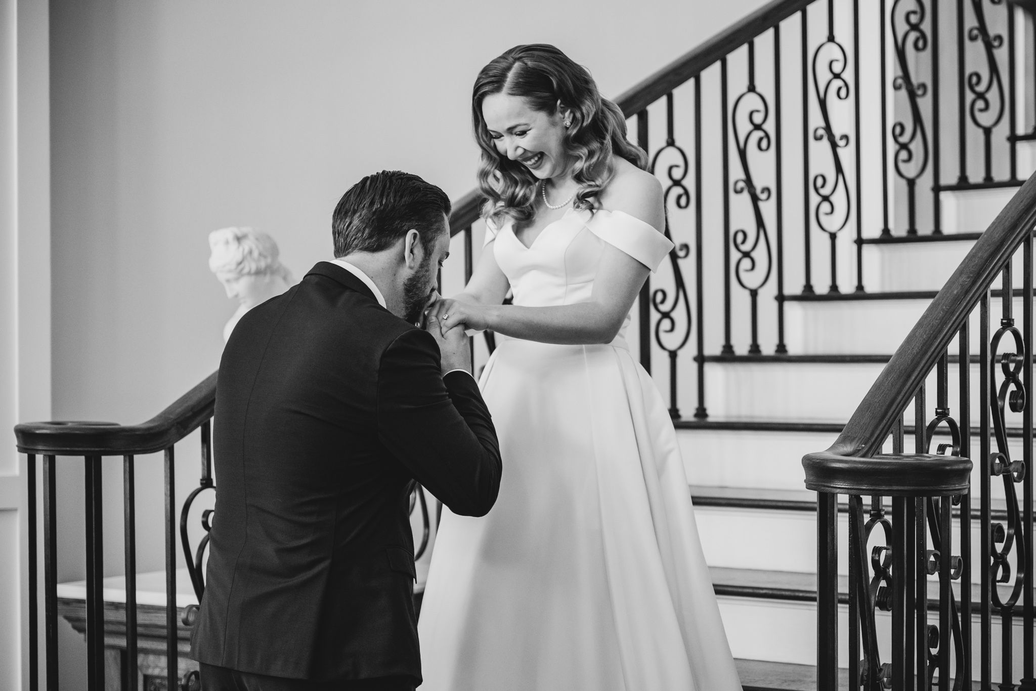 Black and white photo captures emotional first look moment on grand staircase.