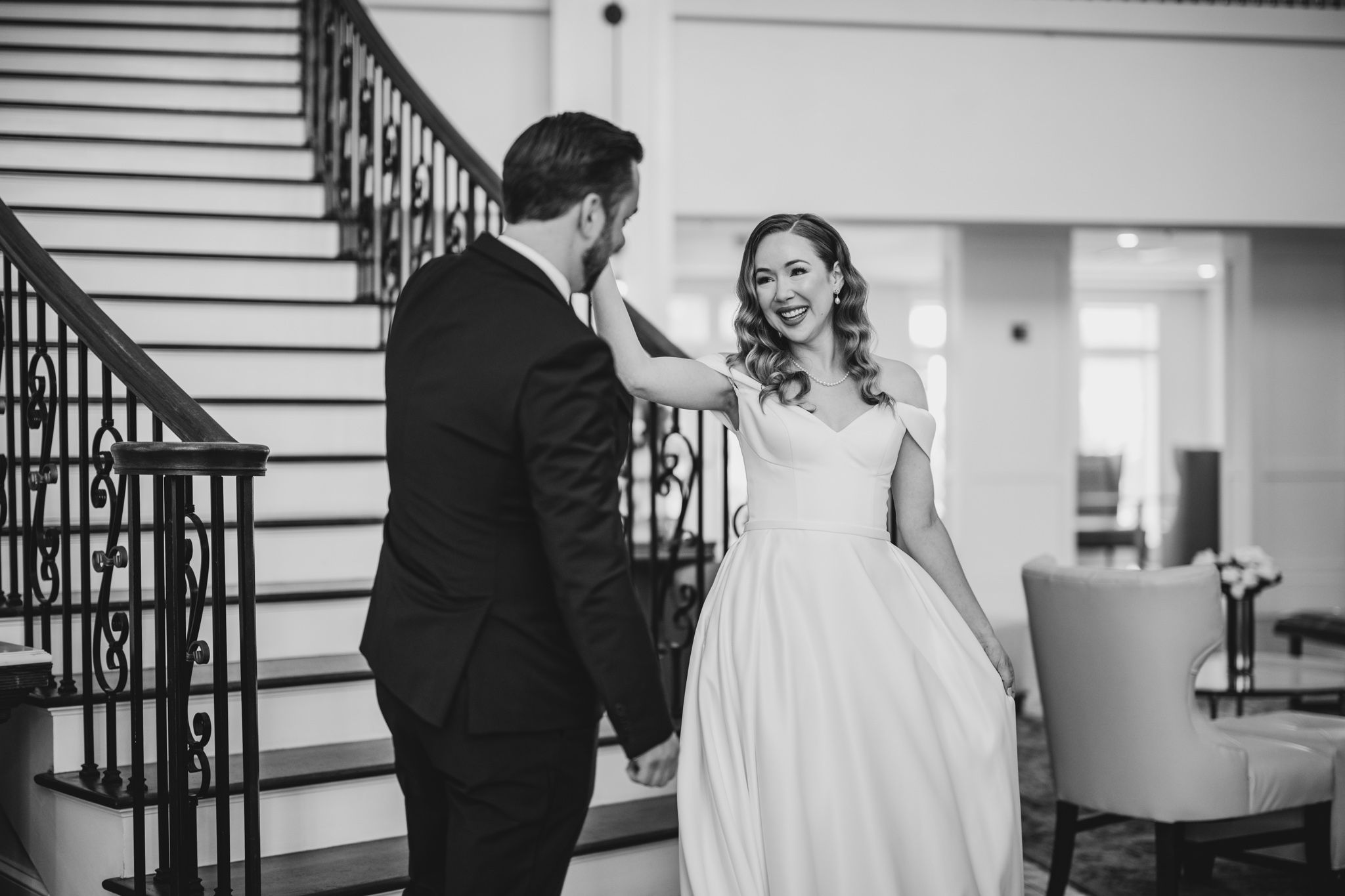 Candid first look wedding moments captured in black and white on classic staircase.