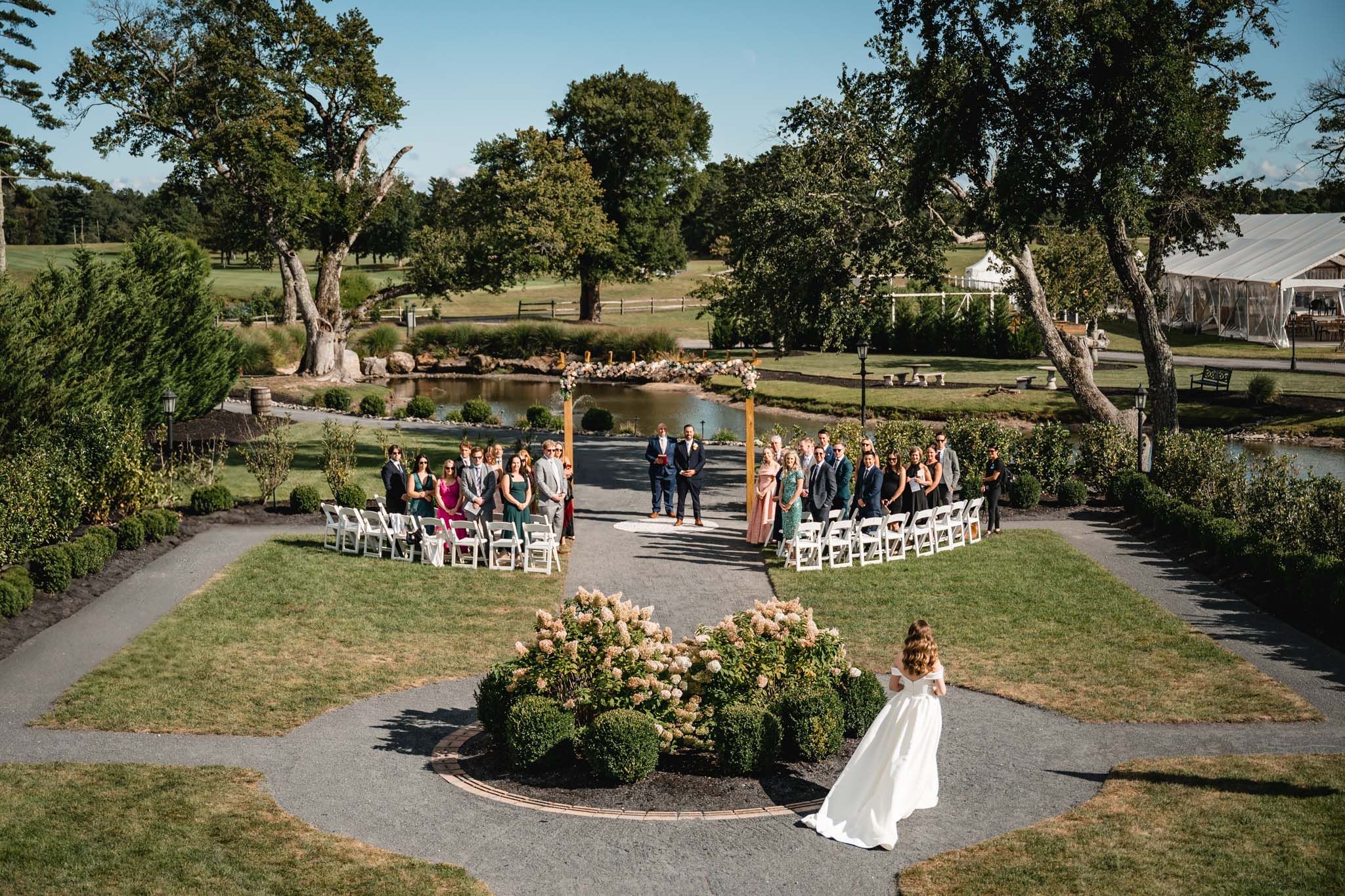 Outdoor wedding ceremony site with white chairs arranged on a lawn under blue skies.