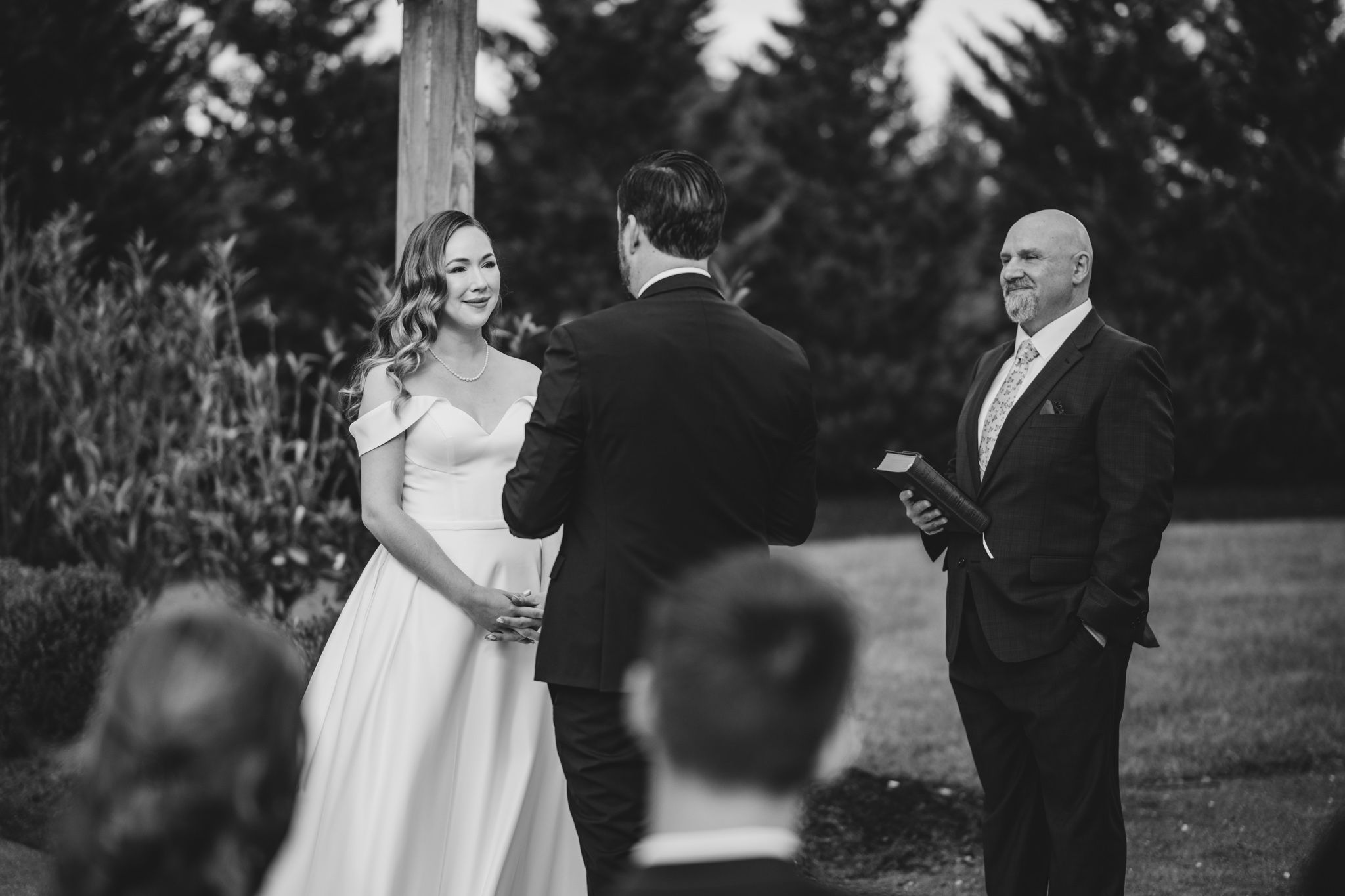 Wedding ceremony taking place among tall evergreen trees.
