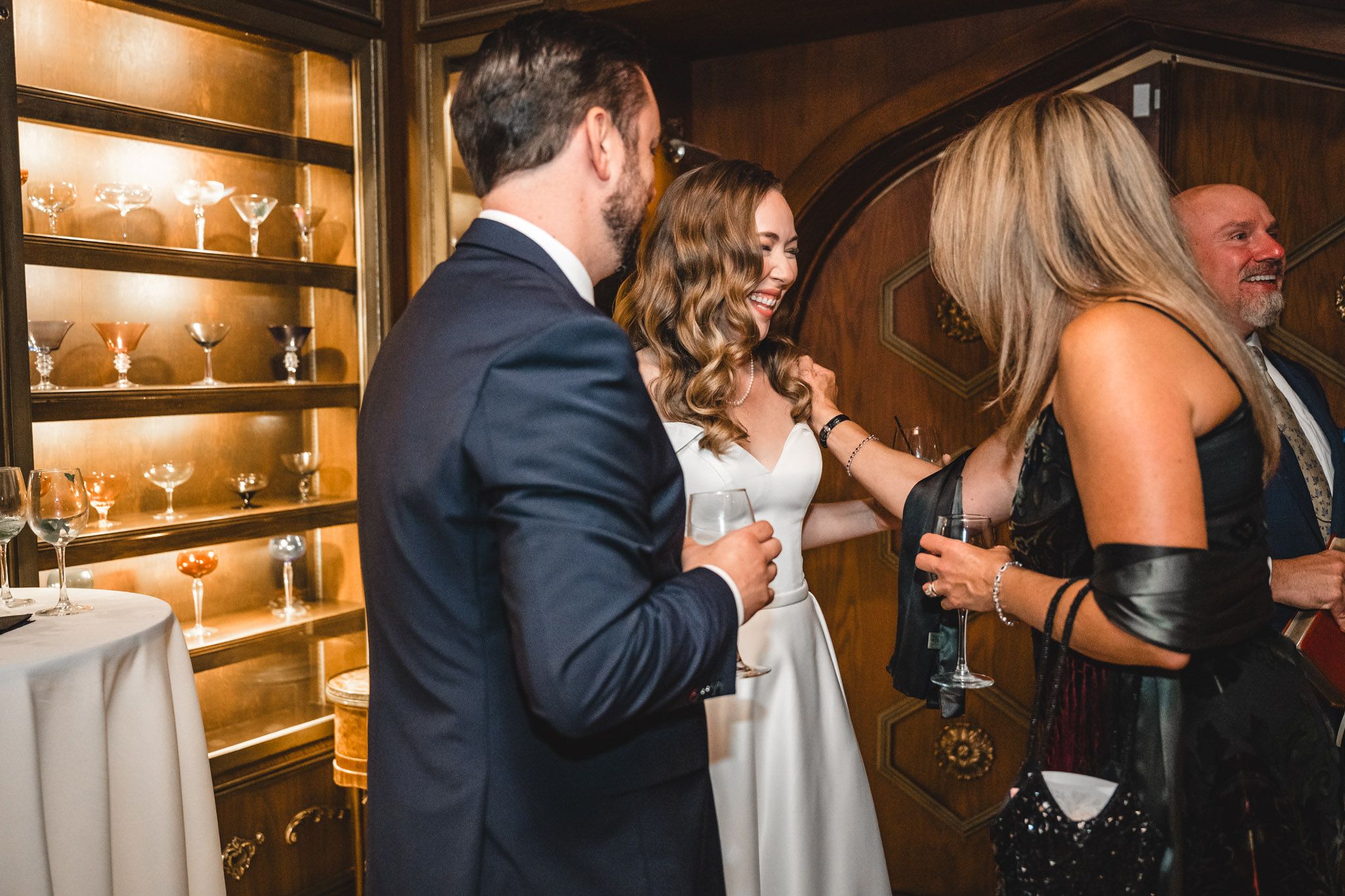 Wedding guests socialize and celebrate in an intimate wood-paneled venue with warm ambient lighting.