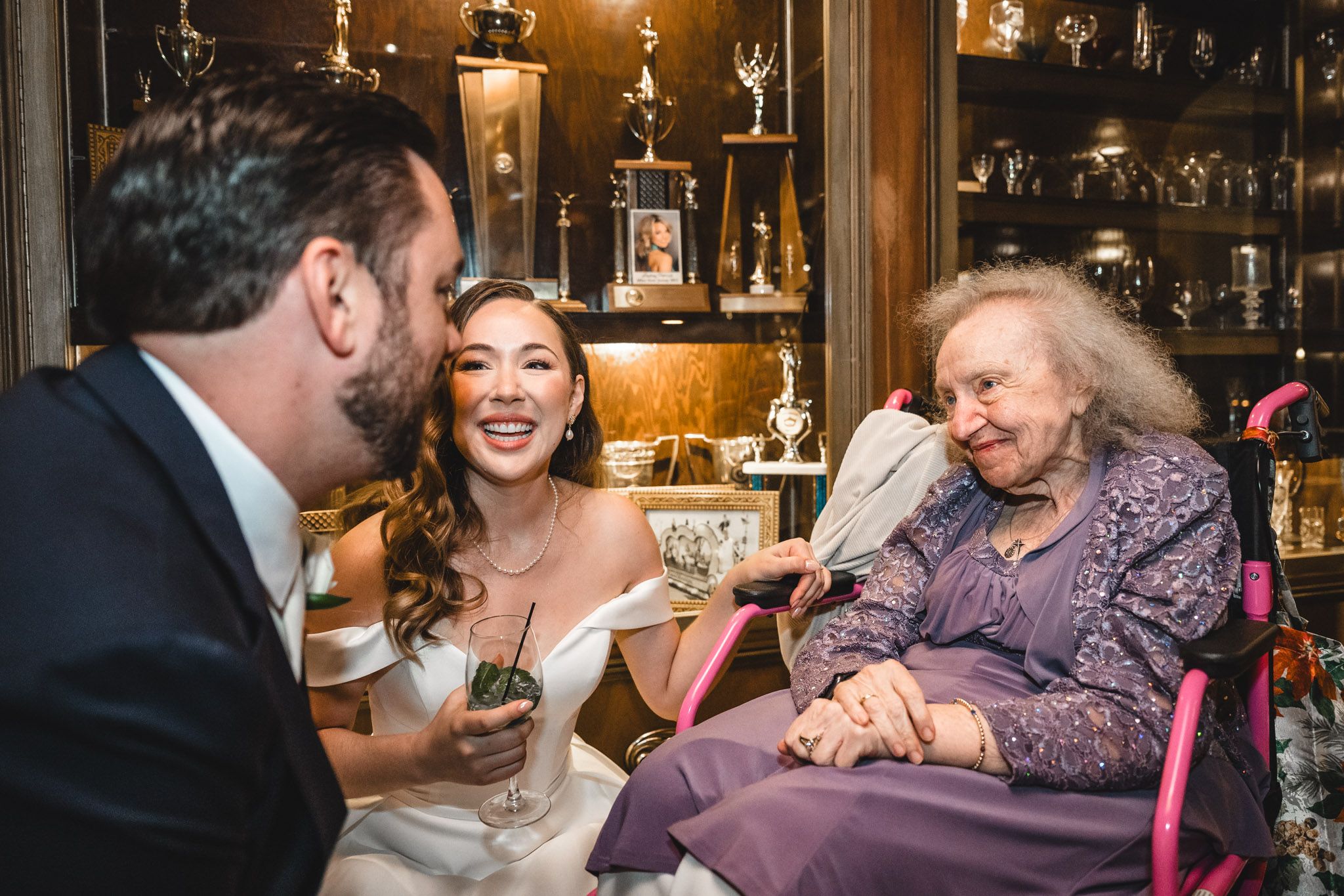 Wedding reception guests mingle and celebrate at a cozy venue with rustic wooden decor and bar area.