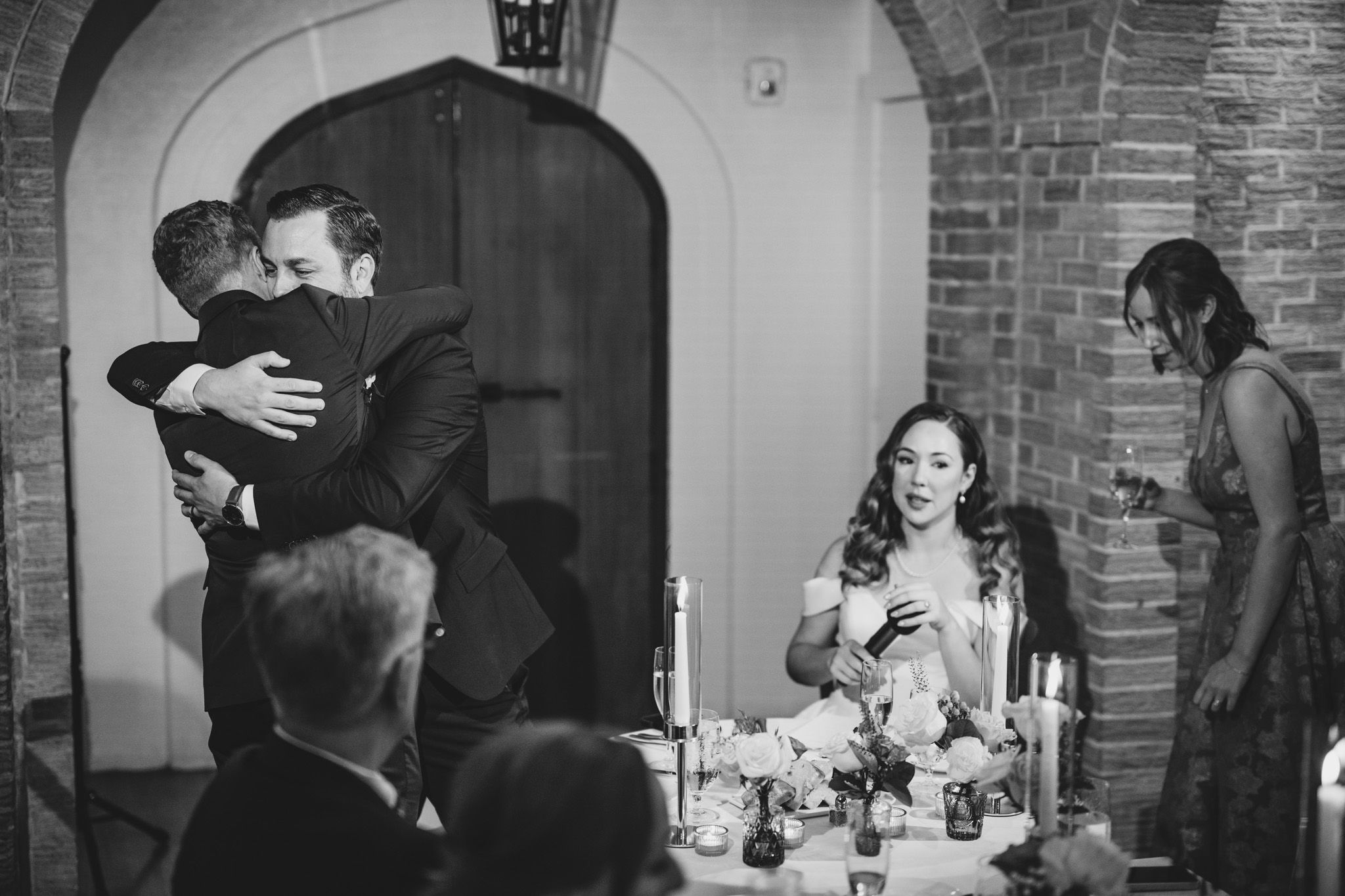 Wedding guests enjoying dinner under arched ceilings in a rustic brick venue.