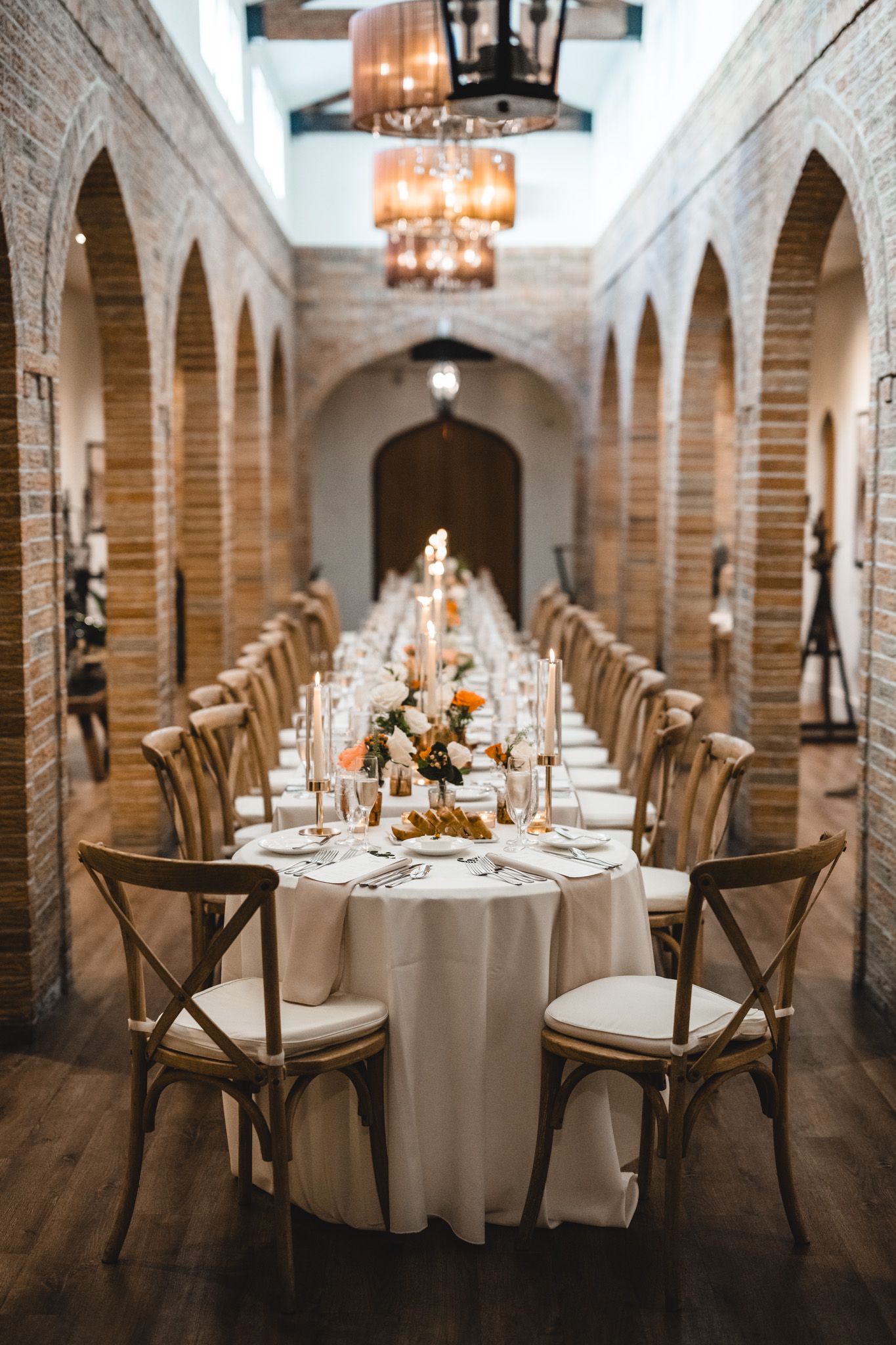 Wedding reception hall featuring brick archways and round tables with classic place settings.