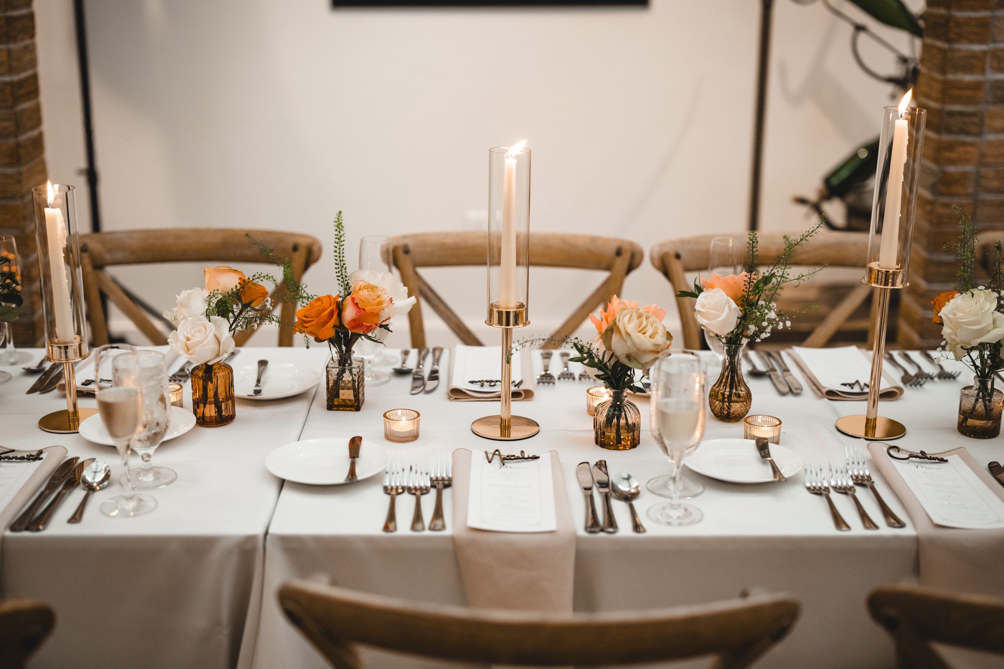 Close-up of elegant table settings with gold accents and white linens at wedding reception.