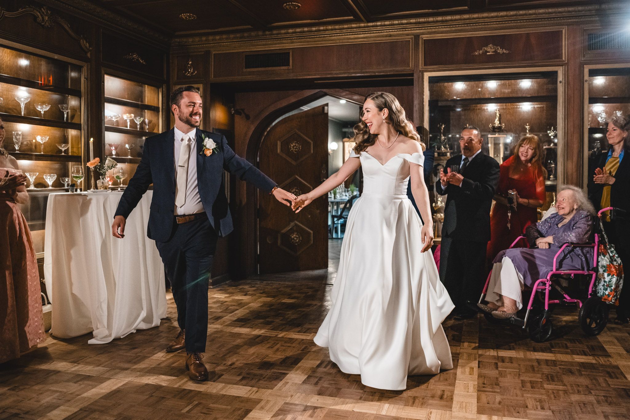 Couples dancing together at an elegant indoor wedding reception with wood paneled ceiling and mood lighting.