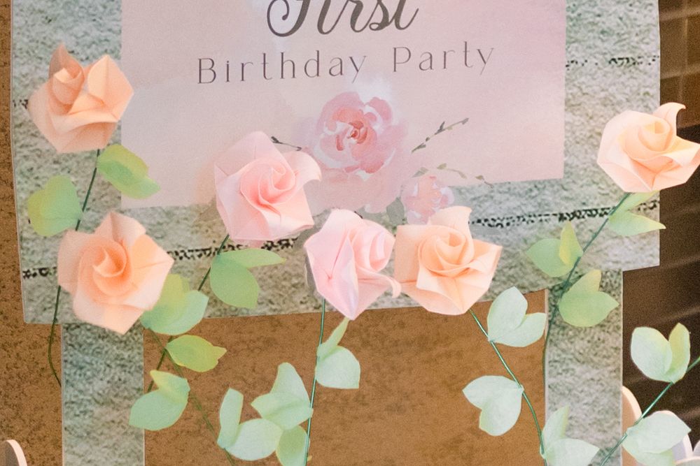 Pink and peach paper roses with green eucalyptus leaves create a whimsical birthday party garland decoration.
