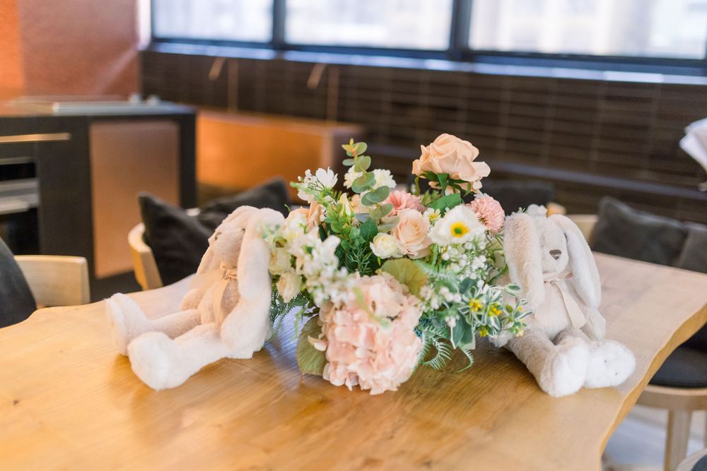 A wedding reception table with white linens and delicate pink and blue floral centerpieces glows under warm lighting.