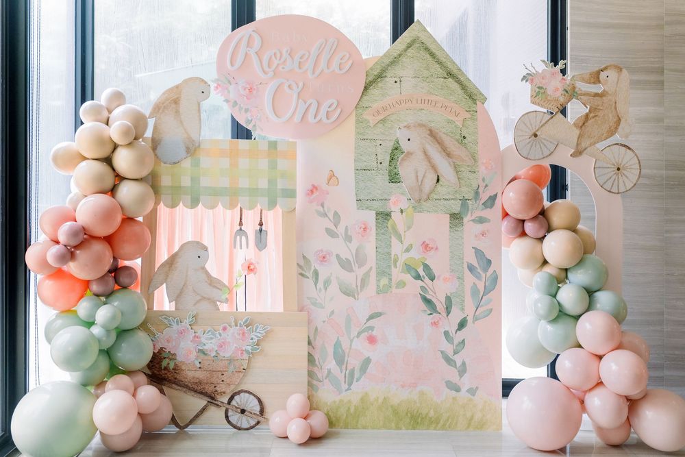 Party space decorated with romantic pastel balloon arch and soft floral patterns features elegant party decor setup.