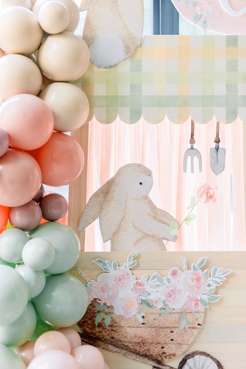 Soft pastel balloon garland with white bunny decorations and floral accents creates an elegant spring party backdrop.