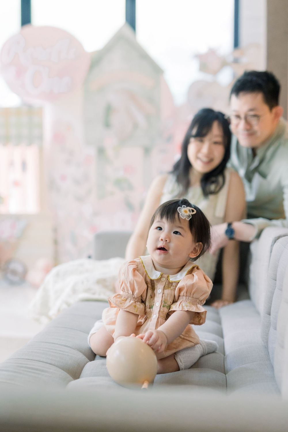 A series of candid family photos showing a young child in a pink outfit playing and relaxing on a white couch.