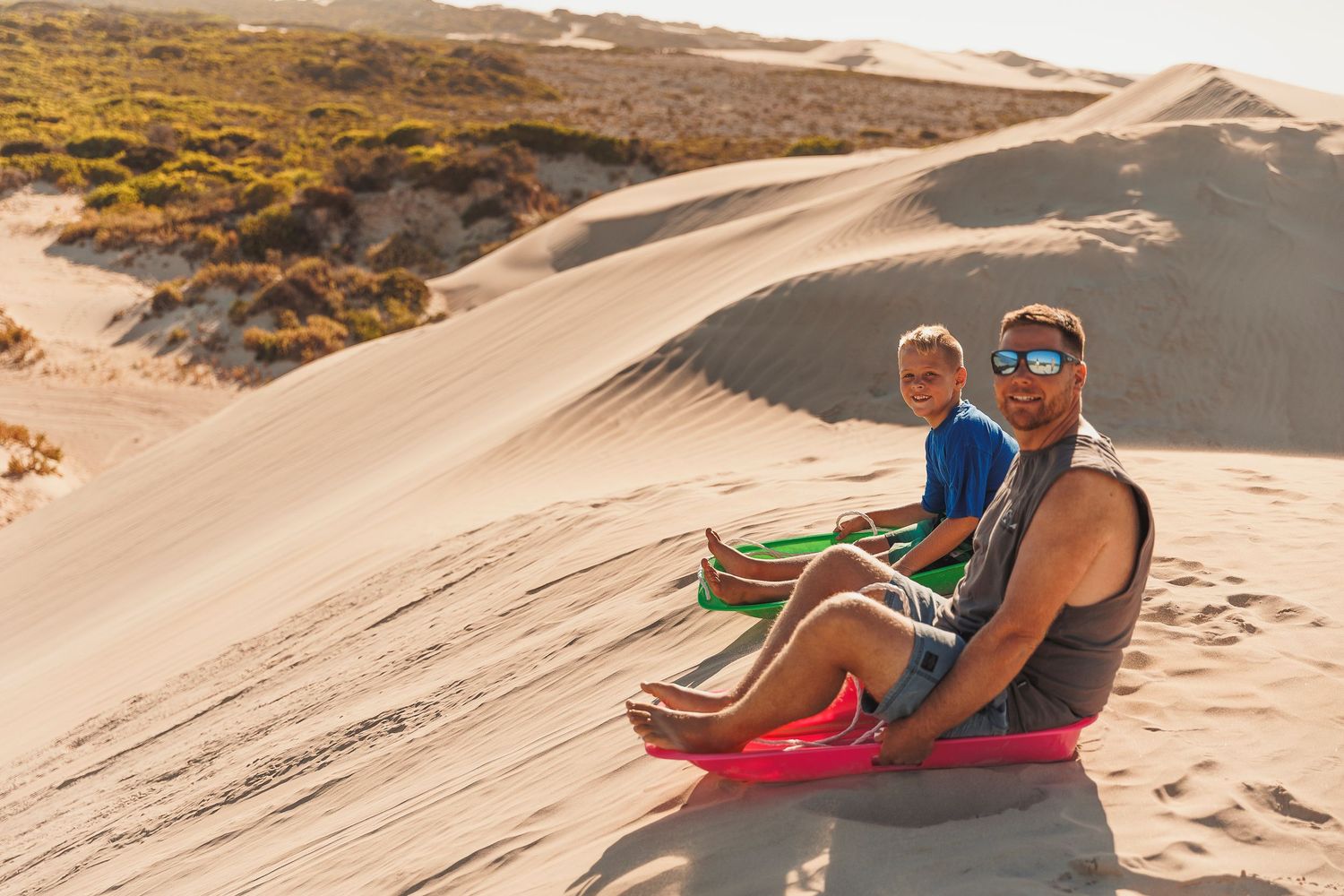 Several frames show sandboarding action on steep desert dunes under bright sunlight.