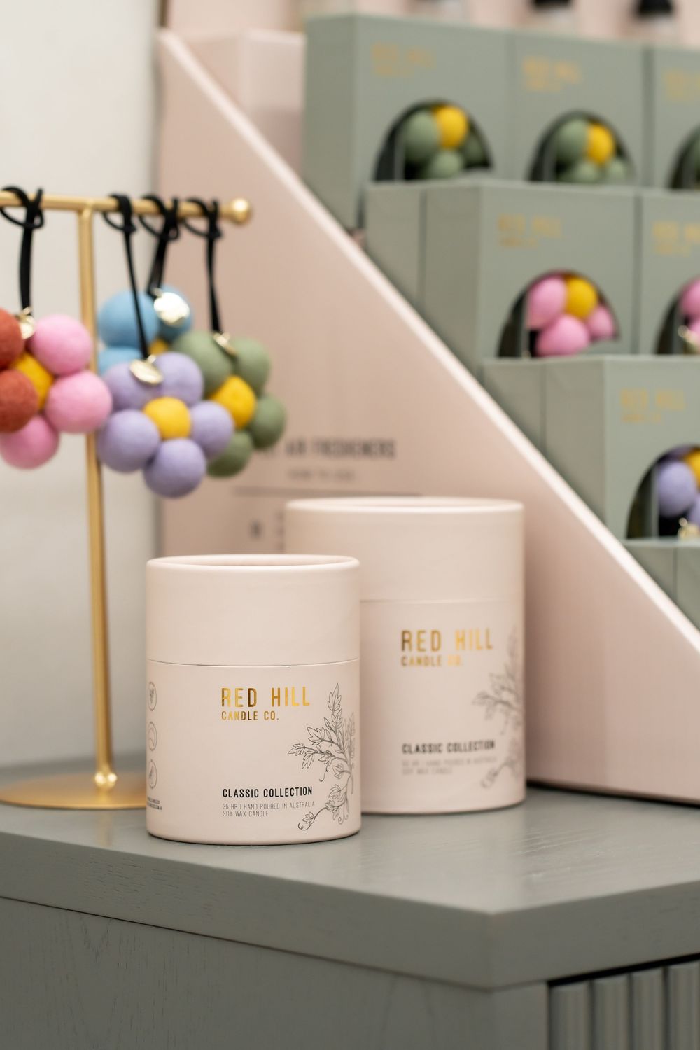 Elegant white skincare product containers with gold accents displayed on gray surface with colorful decorative spheres in background.