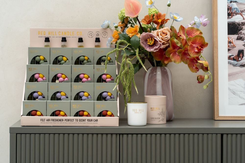 Modern home decor display featuring a floral arrangement in soft peach and coral tones next to graphic art cards on gray sideboard.