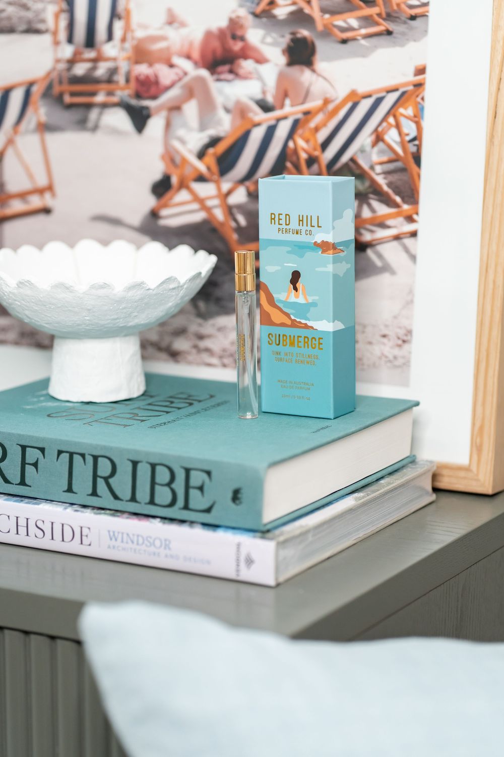Light blue decorative books arranged on a shelf with teal accents and ceramic bowls create an elegant coastal display.