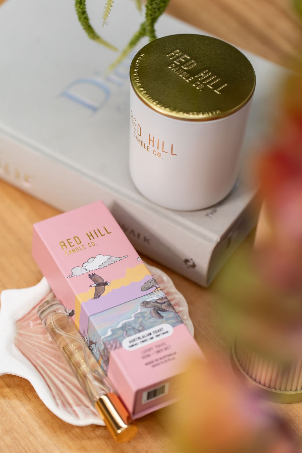 White and pink skincare product packaging with gold accents displayed on wooden surface in natural lighting.