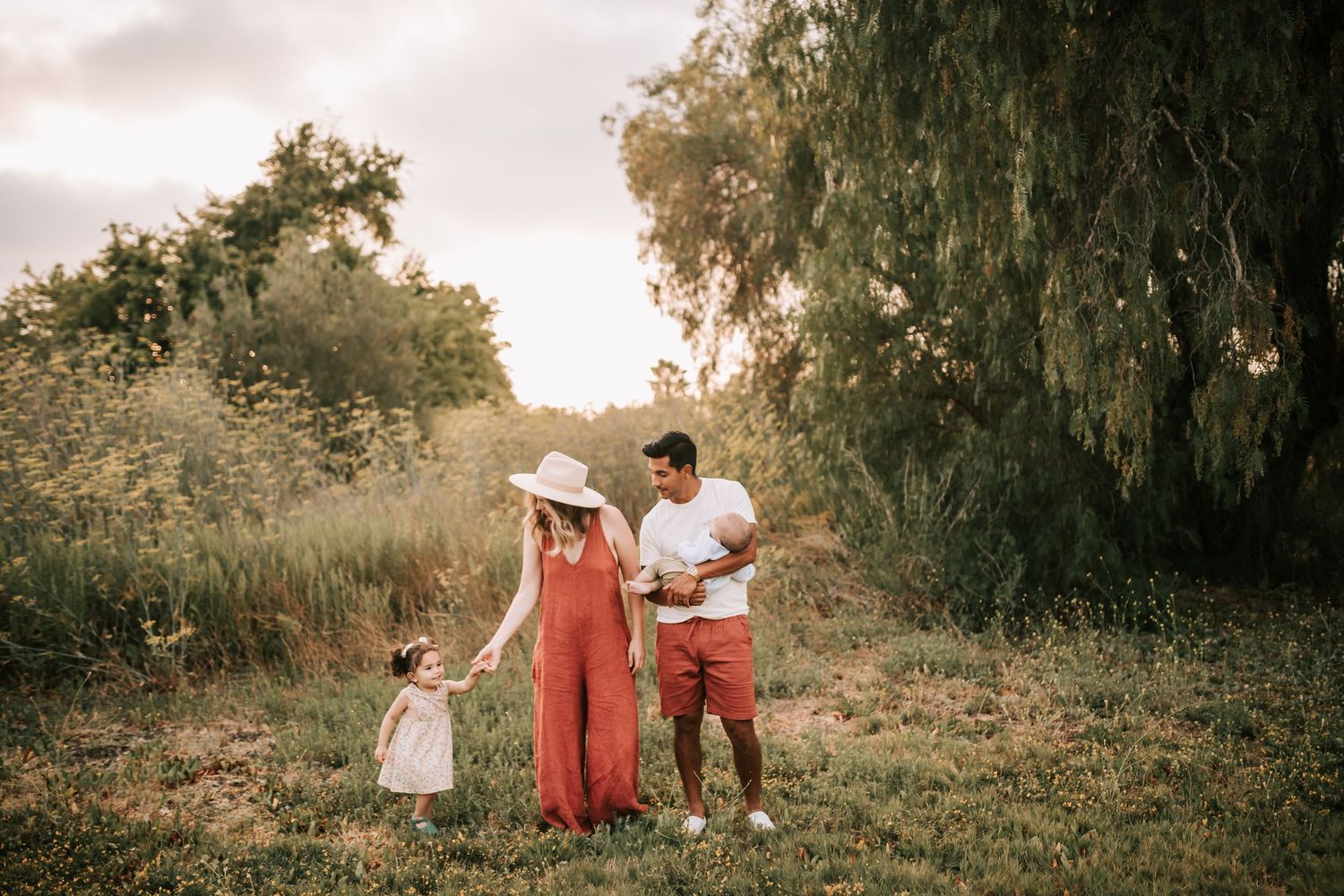 A beautiful family photo session under a warm sunset glow in a rustic wooded setting with autumn tones.