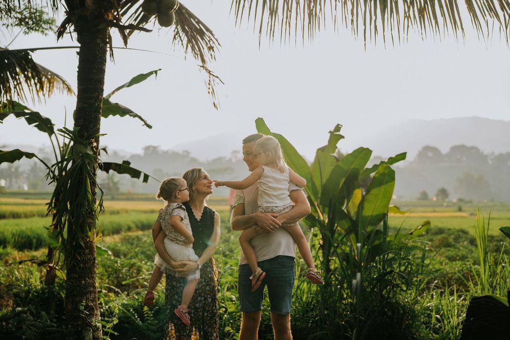 Family enjoying time together in a scenic tropical landscape with mountains in background.