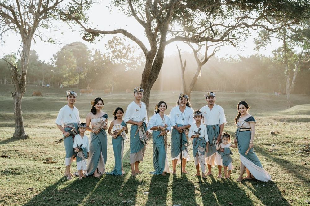Wedding party posing under trees at sunset creating long shadows.