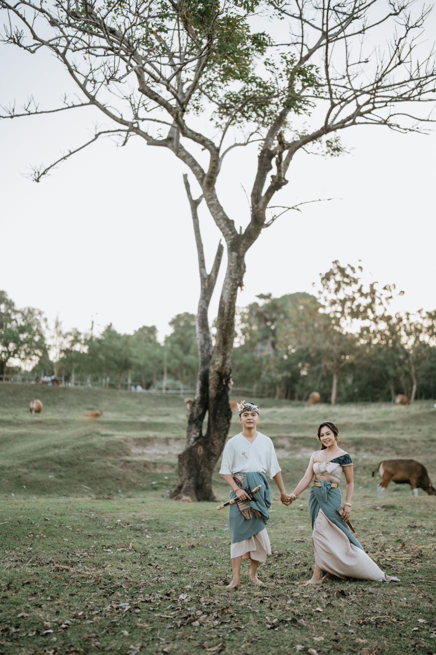 People in coordinated outfits walk through a scenic field with scattered trees.