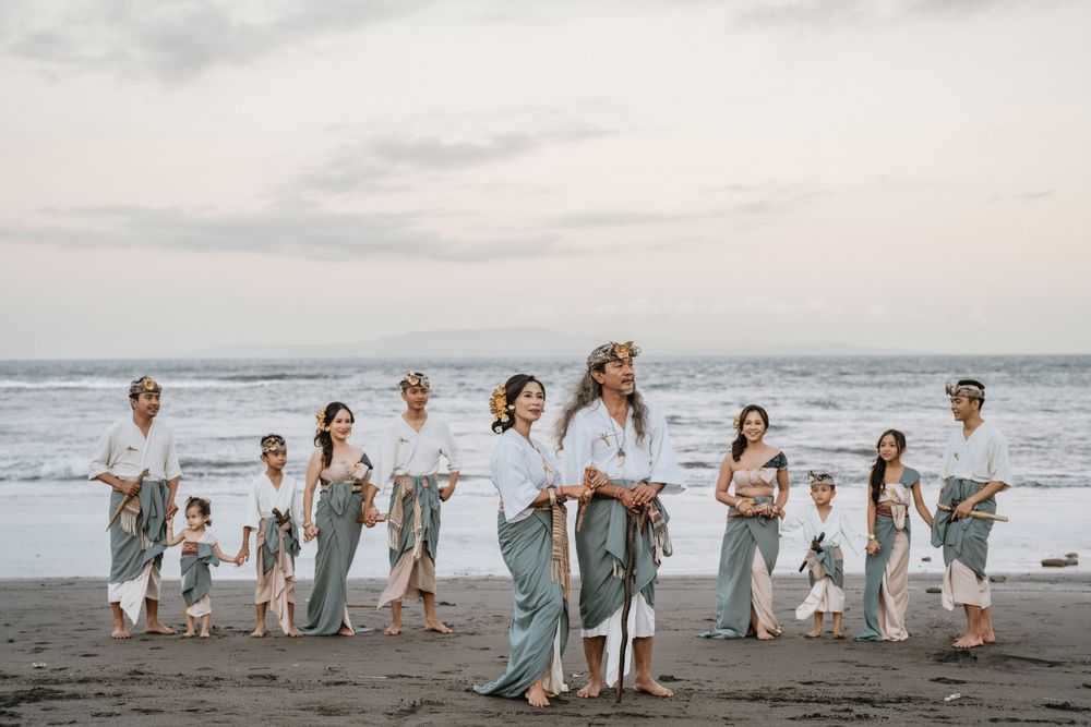 A group in matching outfits walks along a beach at sunset.