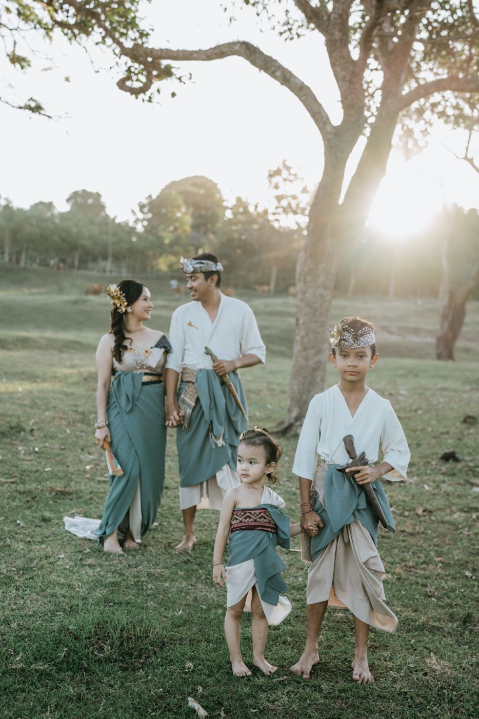 A family group in matching outfits enjoys a playful moment together in a park setting.